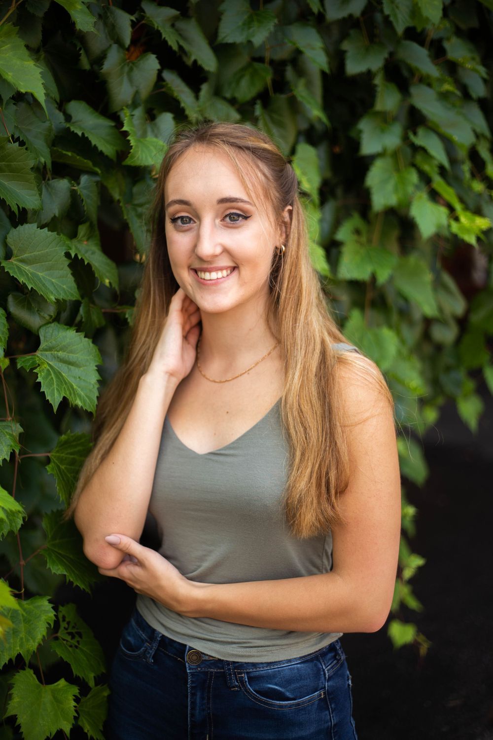 Portrait series against green vine backdrop with casual tank top and natural lighting. Mauston photographer.