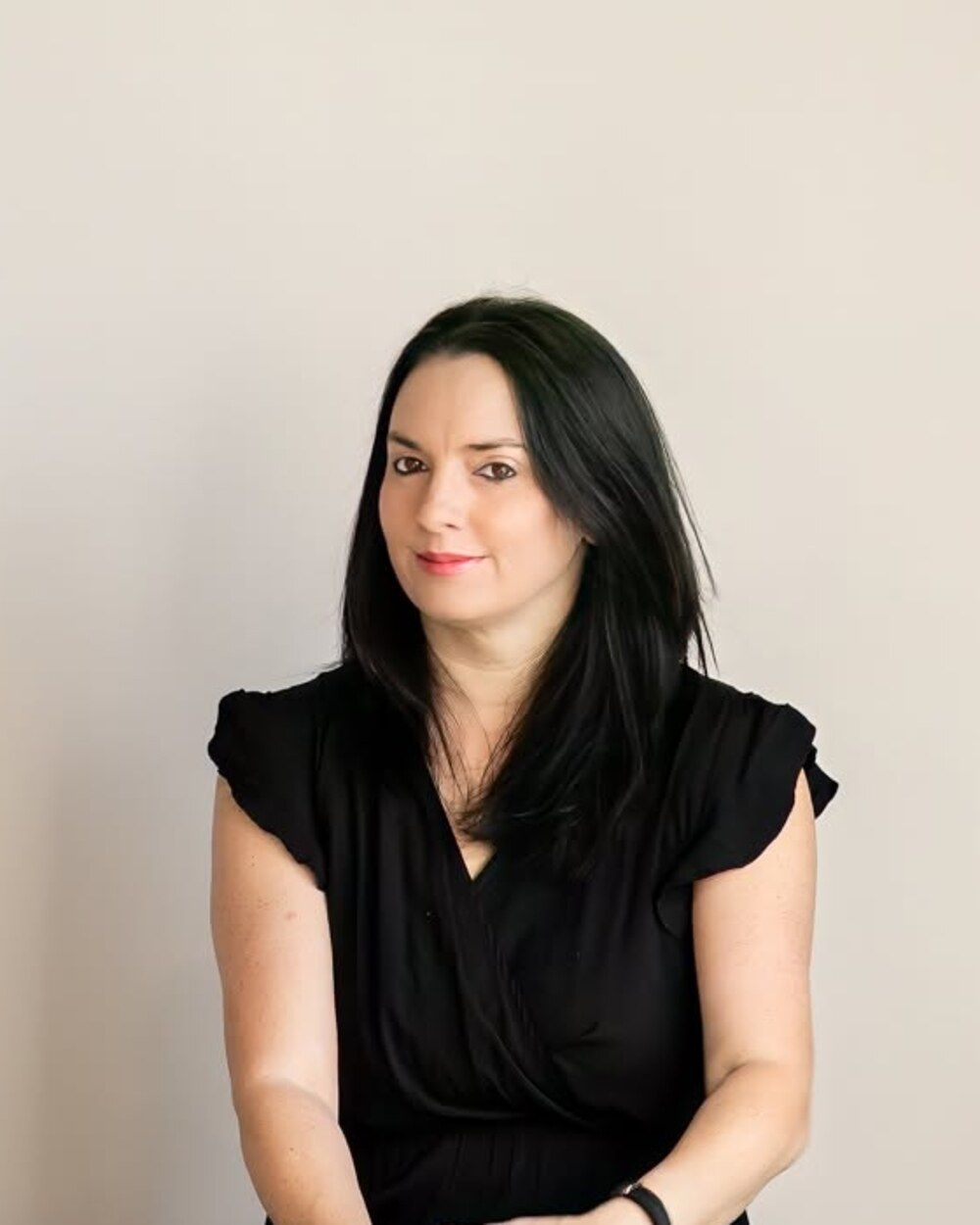 Professional woman with dark hair wearing a black top, posed against a neutral background.
