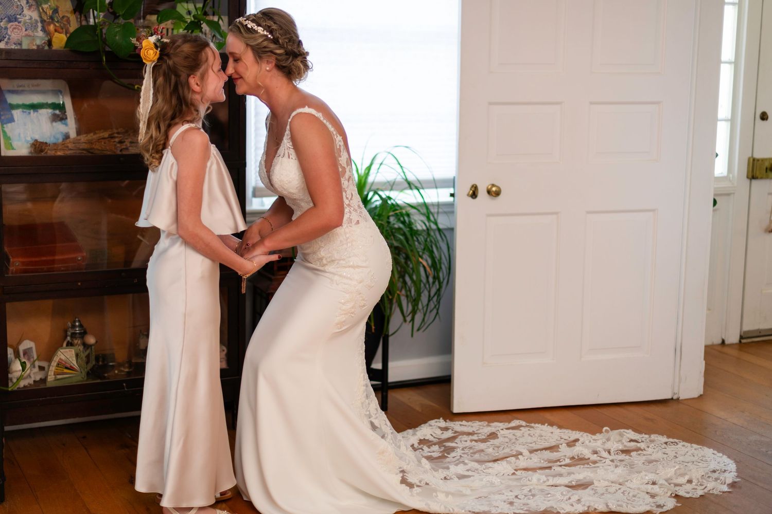 Two brides in white wedding gowns share an intimate moment holding hands indoors on their wedding day.
