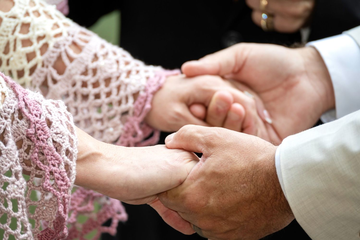 Close-up of a groom placing a wedding ring on the bride's finger during a ceremony.