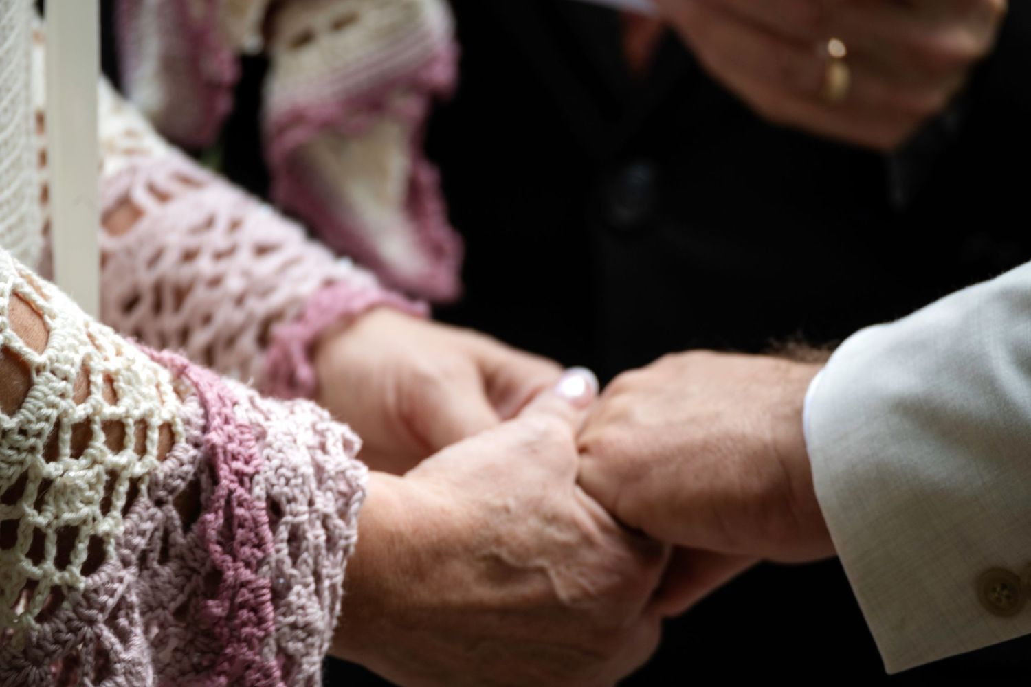 Elderly couple holding hands tenderly, wearing lace and formal attire, symbolizing lasting love and companionship.