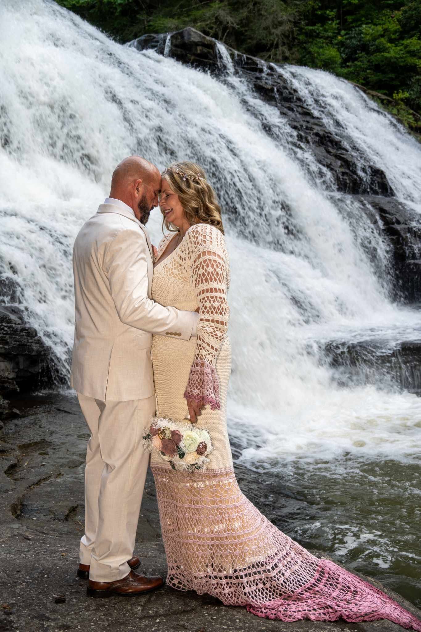 Couple in wedding attire sharing tender moment in front of stunning rushing waterfall backdrop. Tennessee - Fall Creek Falls State Park