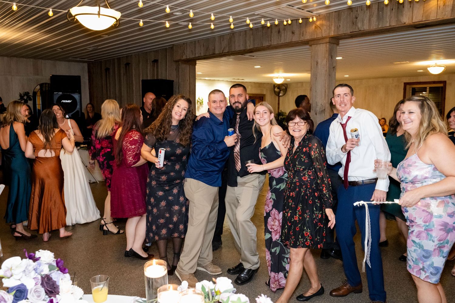 Happy wedding guests pose together smiling at lively reception celebration.