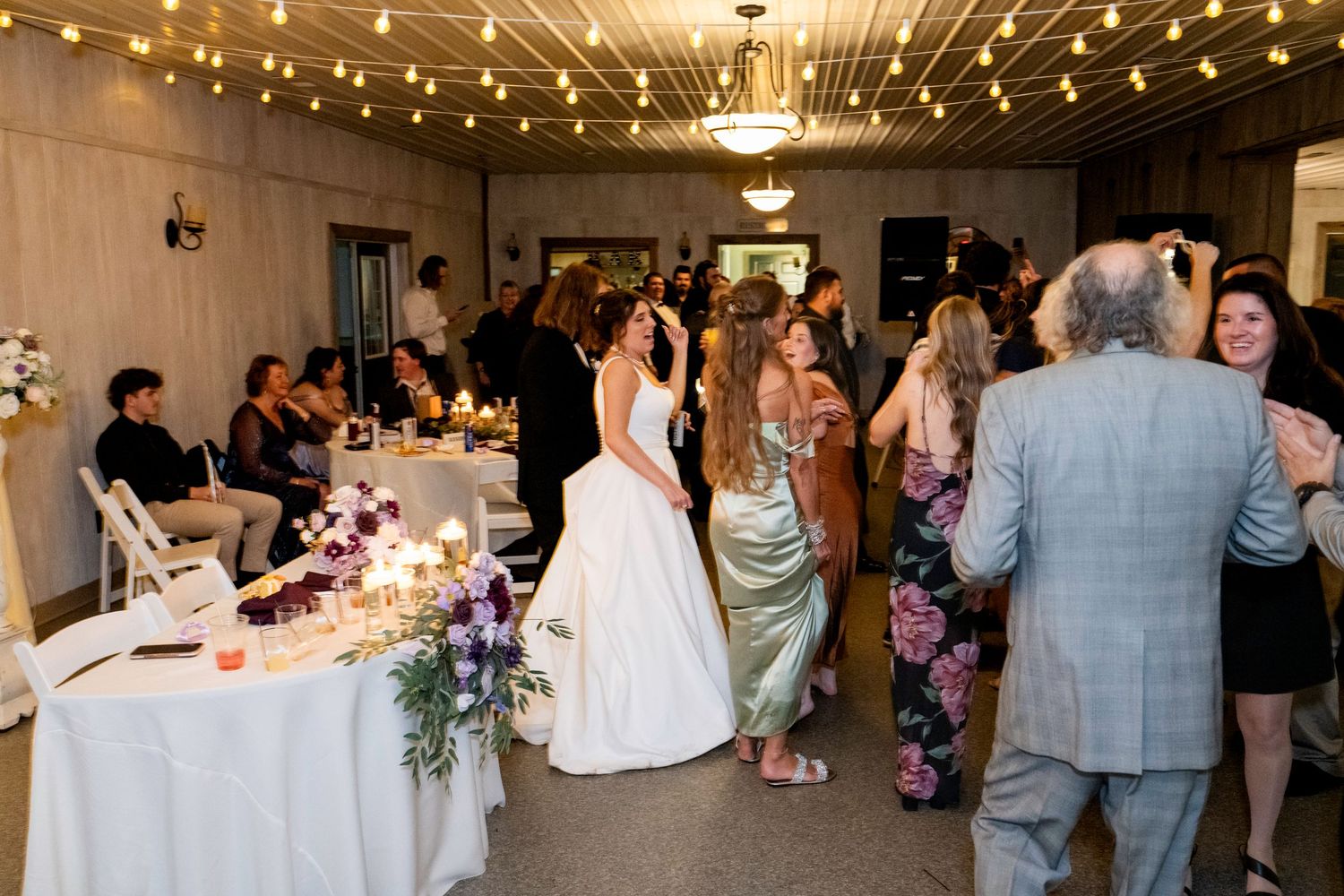 Bride mingles with guests on busy wedding reception dance floor.