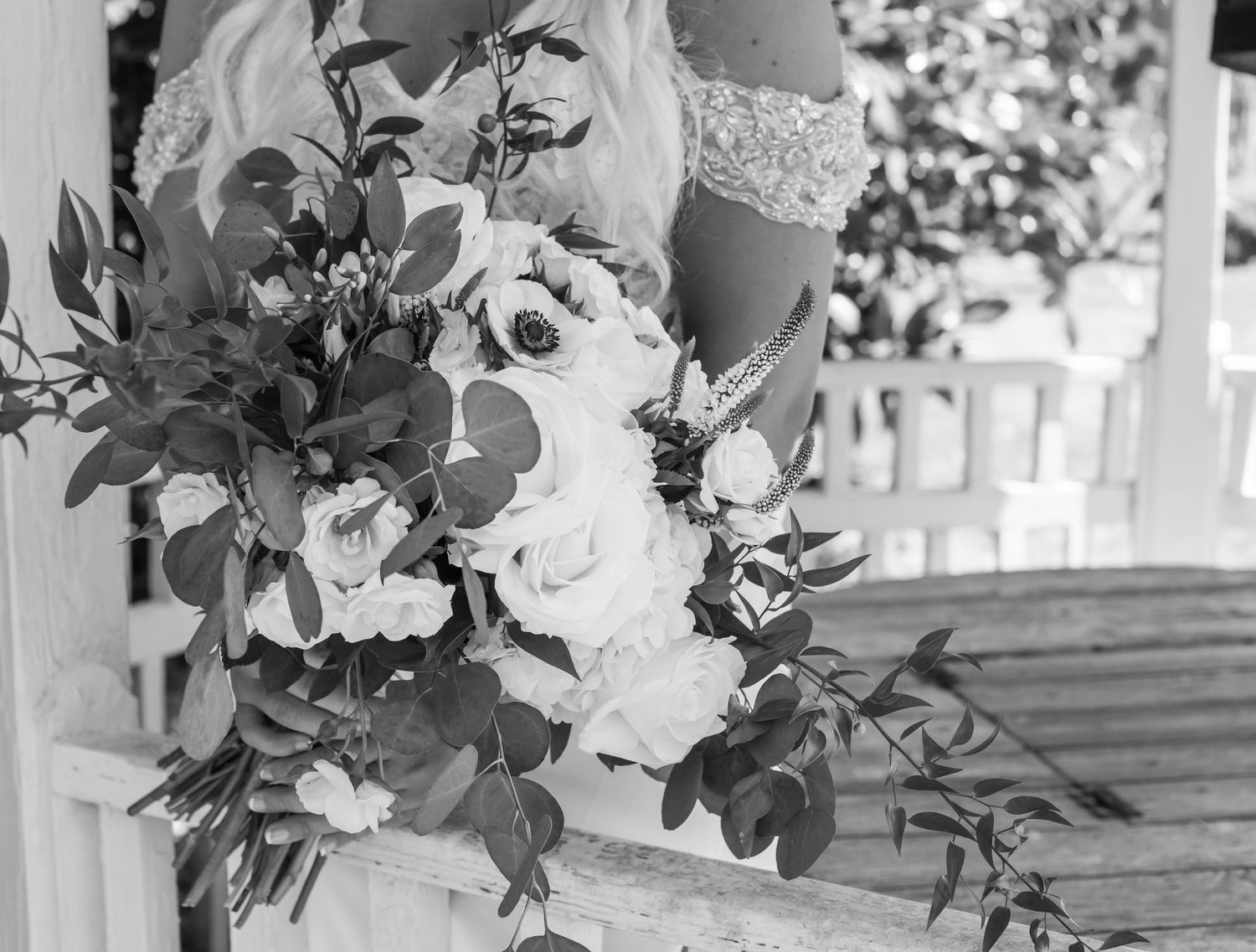 Black and white image of a cascading bridal bouquet with white roses and eucalyptus.