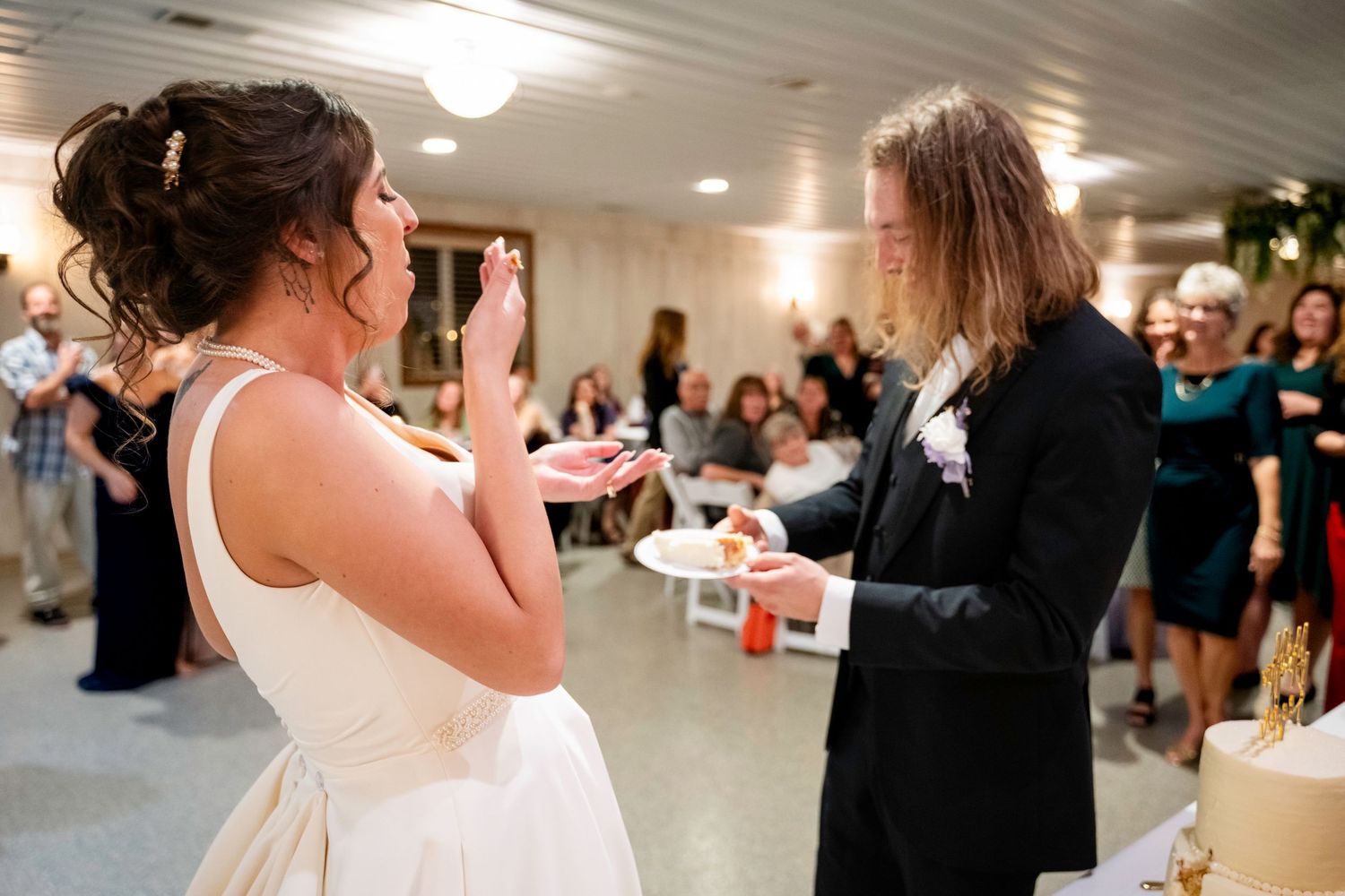 Bride and groom share a playful moment during wedding cake cutting ceremony.