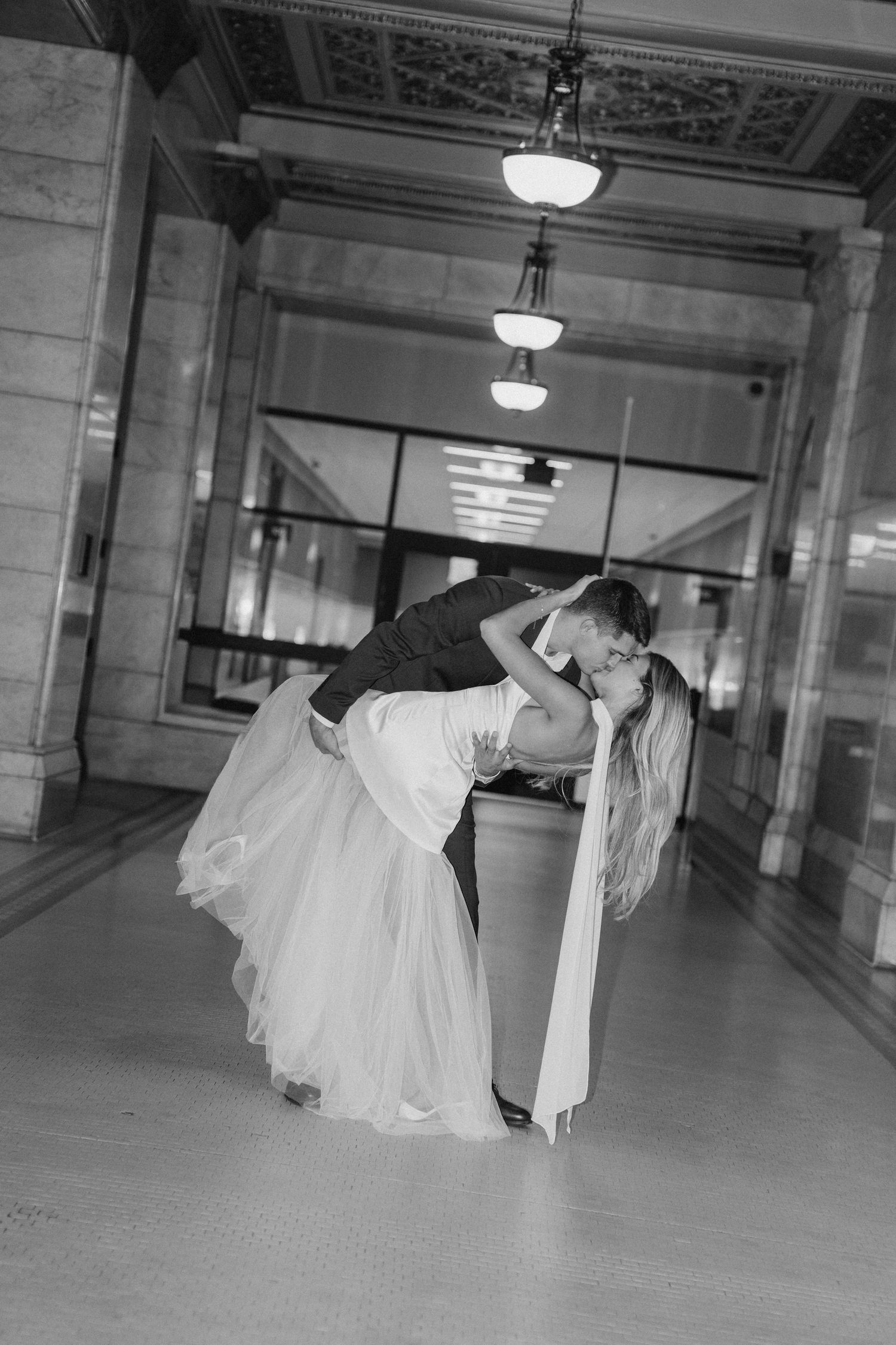 Artistic black and white dance sequence showing a couple performing dramatic lifts in an empty hall.