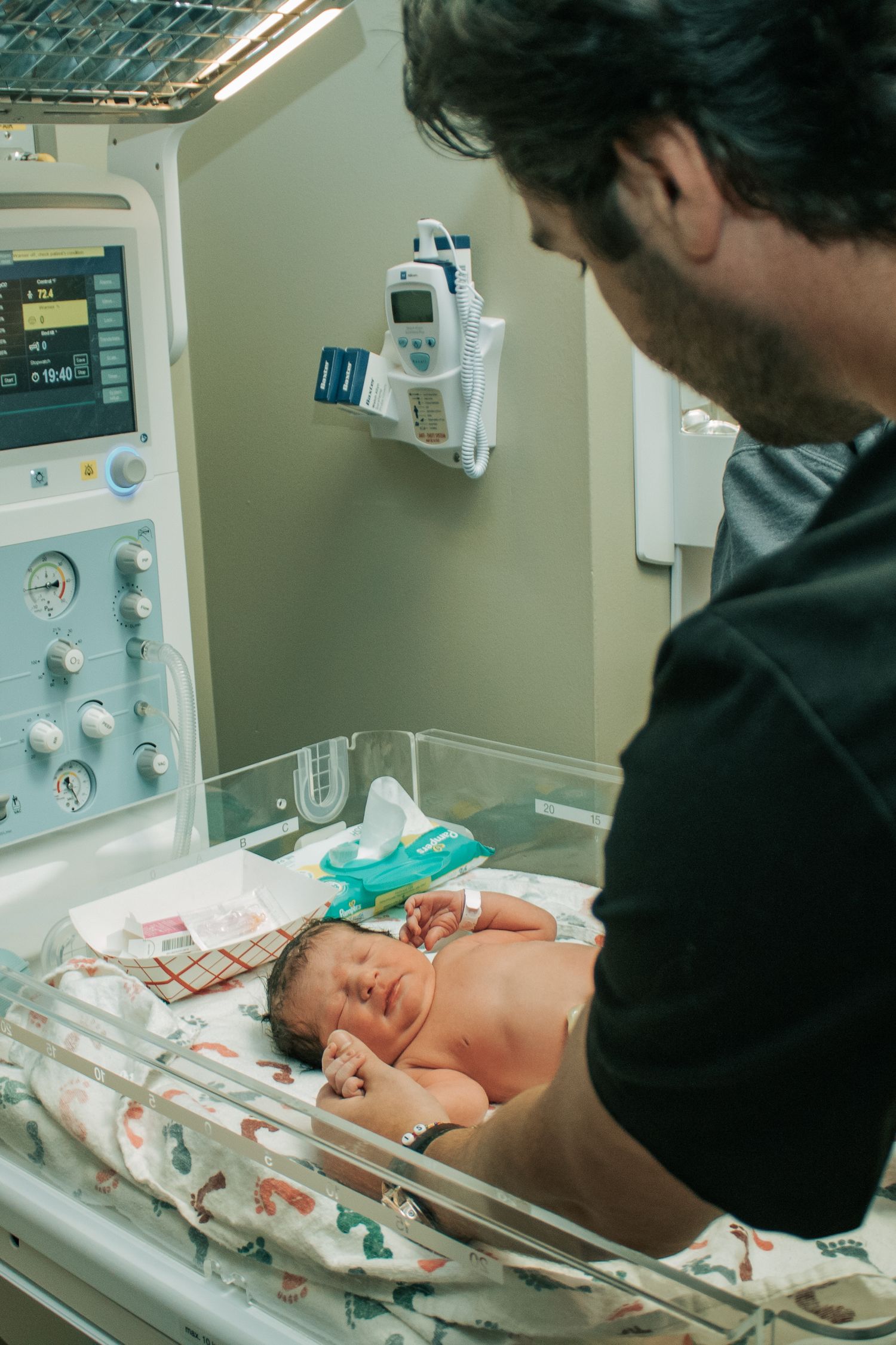 Copperas Cove Birth Photographer father holding baby's hand in baby warmer.