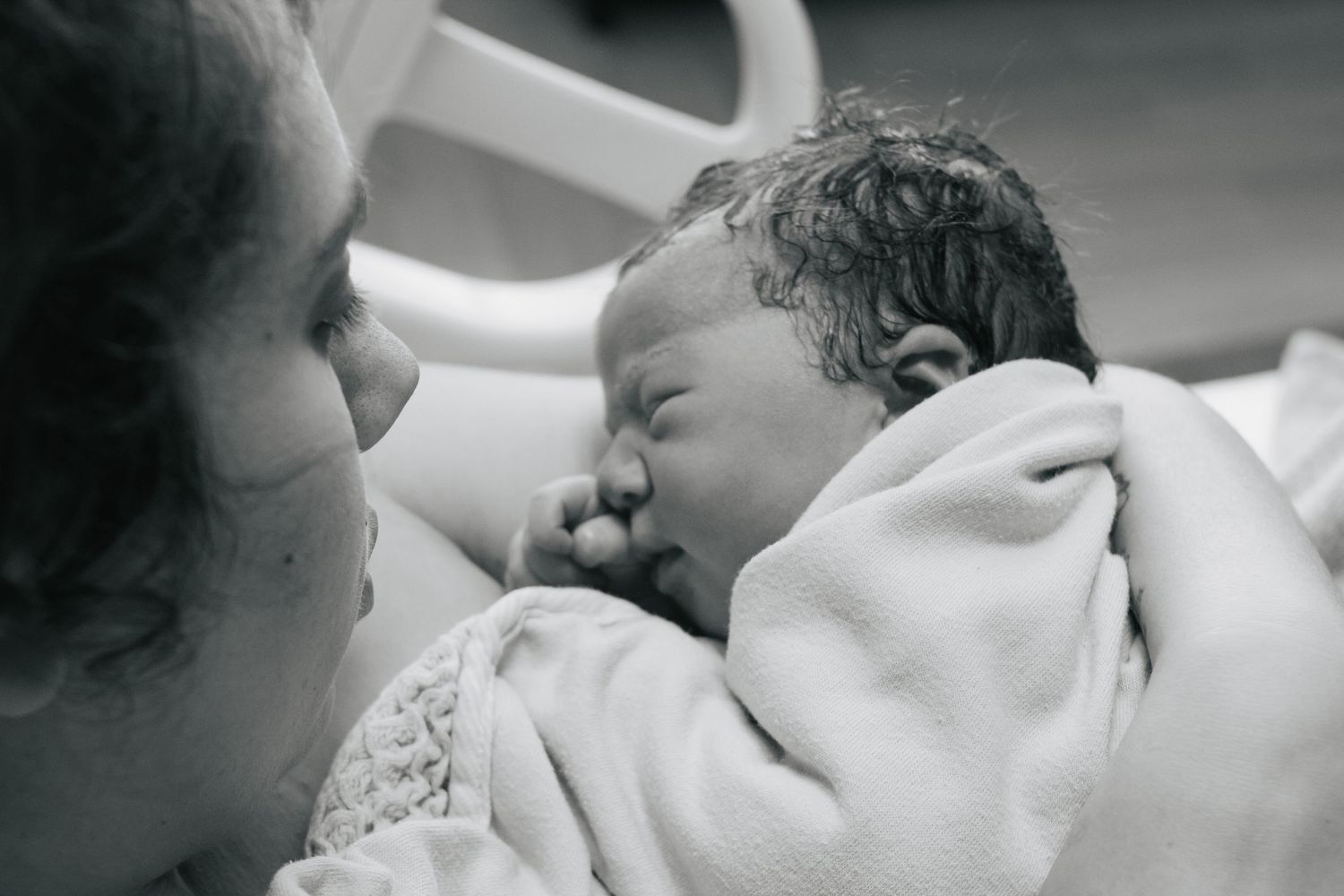 Fort Hood Birth Photographer captures mother holding newborn baby in a hospital bed.