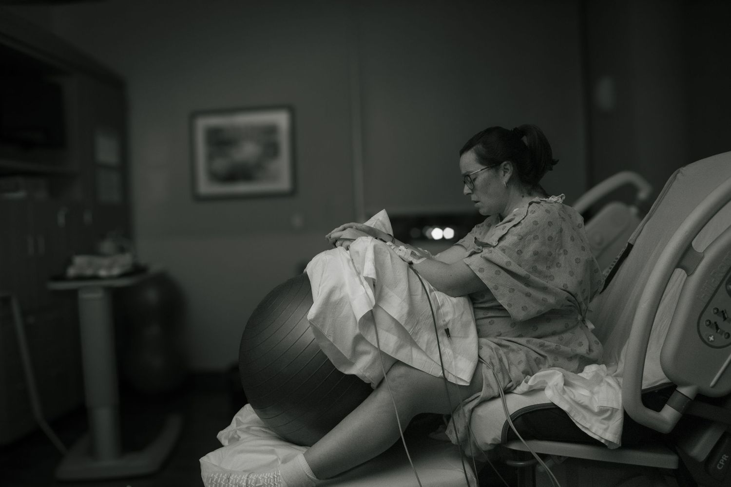 Copperas Cove birth photographer capturing a pregnant woman using a birthing ball during labor in hospital.