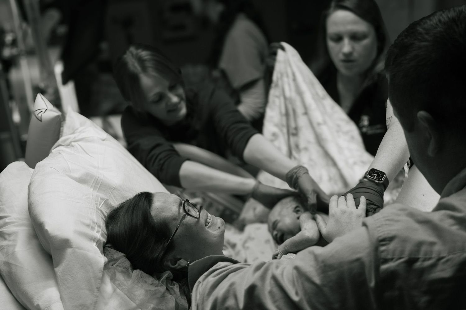 Copperas Cove Birth Photographer captures mother holding baby for first time, supported by husband and surrounded by hospital staff