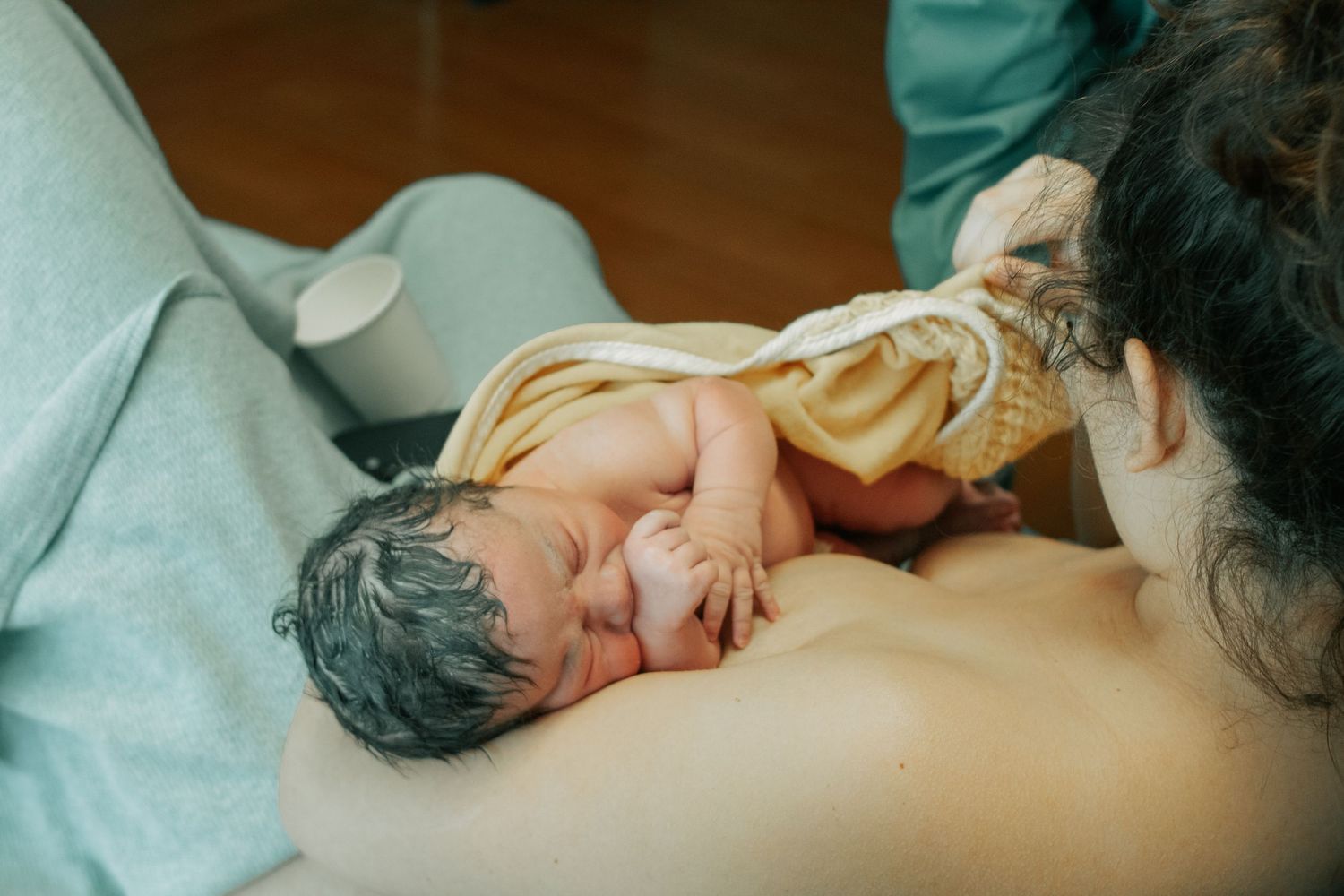 Fort Hood Birth Photographer captures baby sucking on hand in mother's arms at the hospital moments after birth.