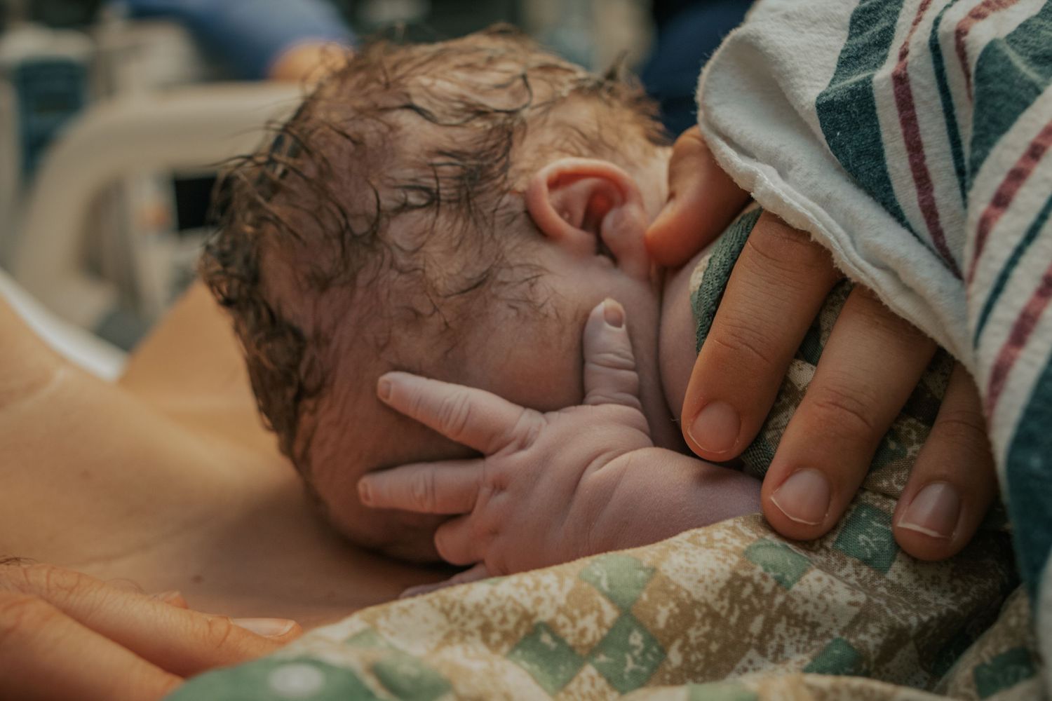 Georgetown Birth Photographer captures baby hiding his face with his adorable little hand while laying on his mom's chest.