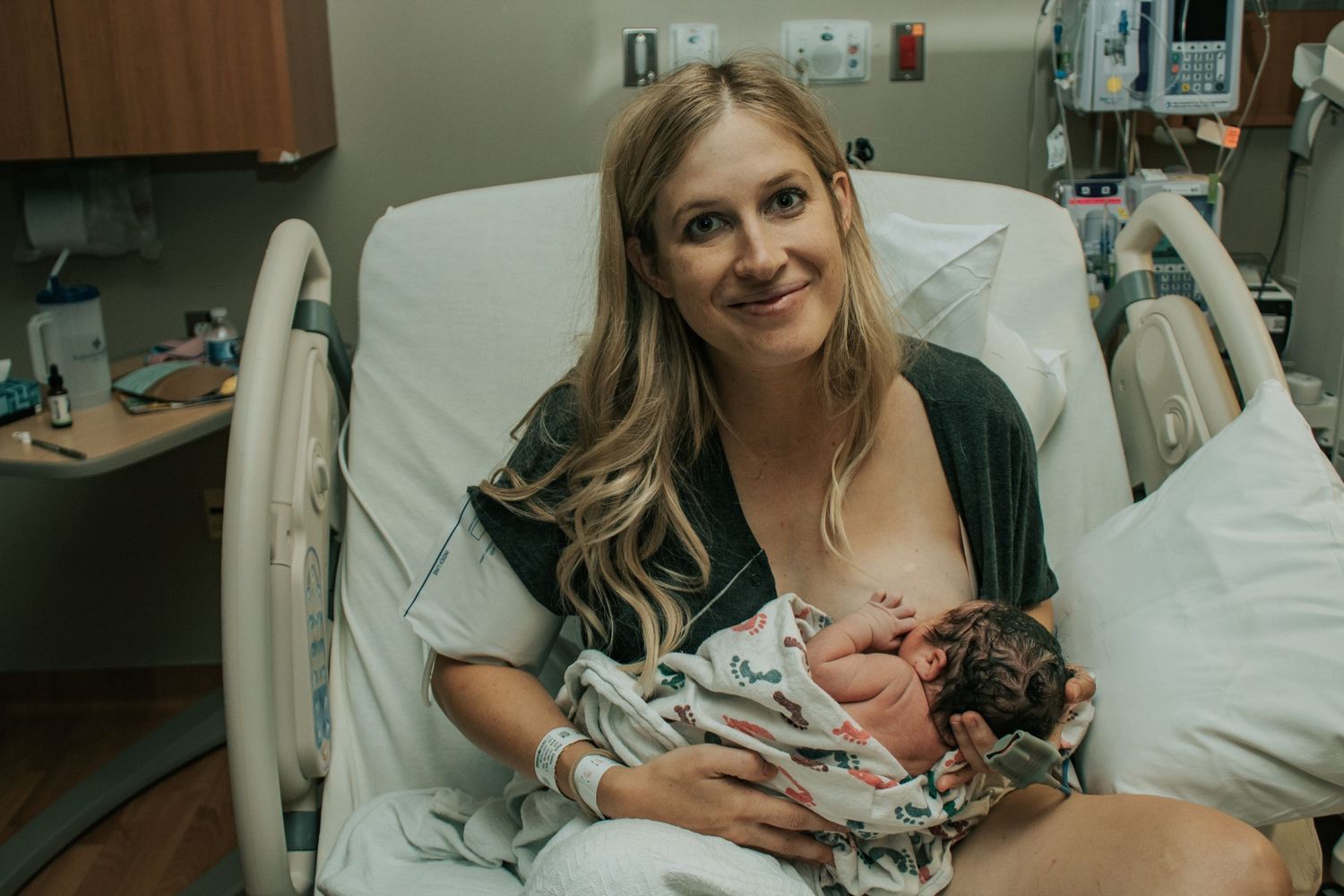Copperas Cove Birth Photographer captures mother breastfeeding and smiling at the camera