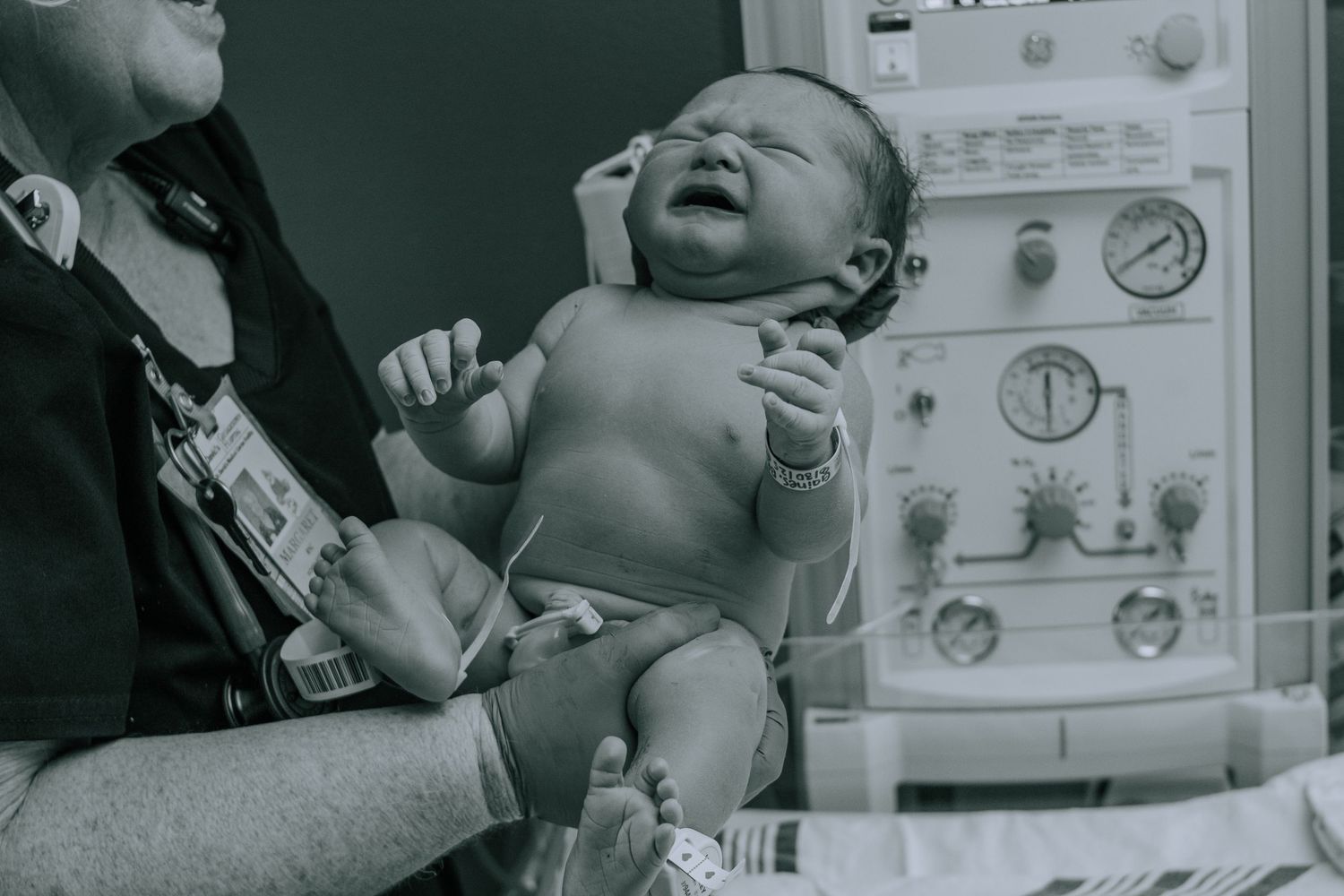 Georgetown Birth Photographer captures newborn baby being help by the nurse.