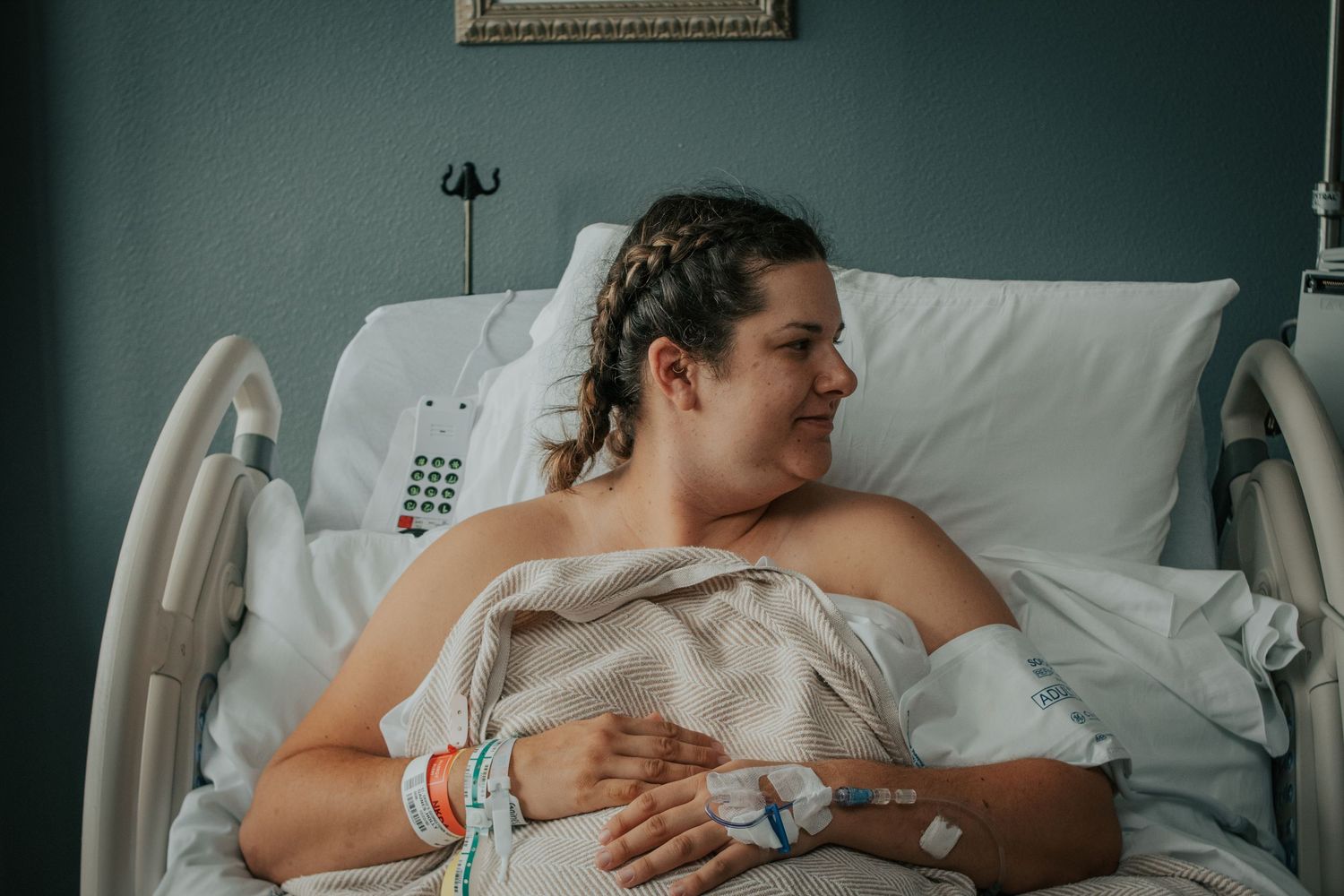 Georgetown Birth Photographer captures mother admiring her baby while it's being measured and weighed in the warmer.