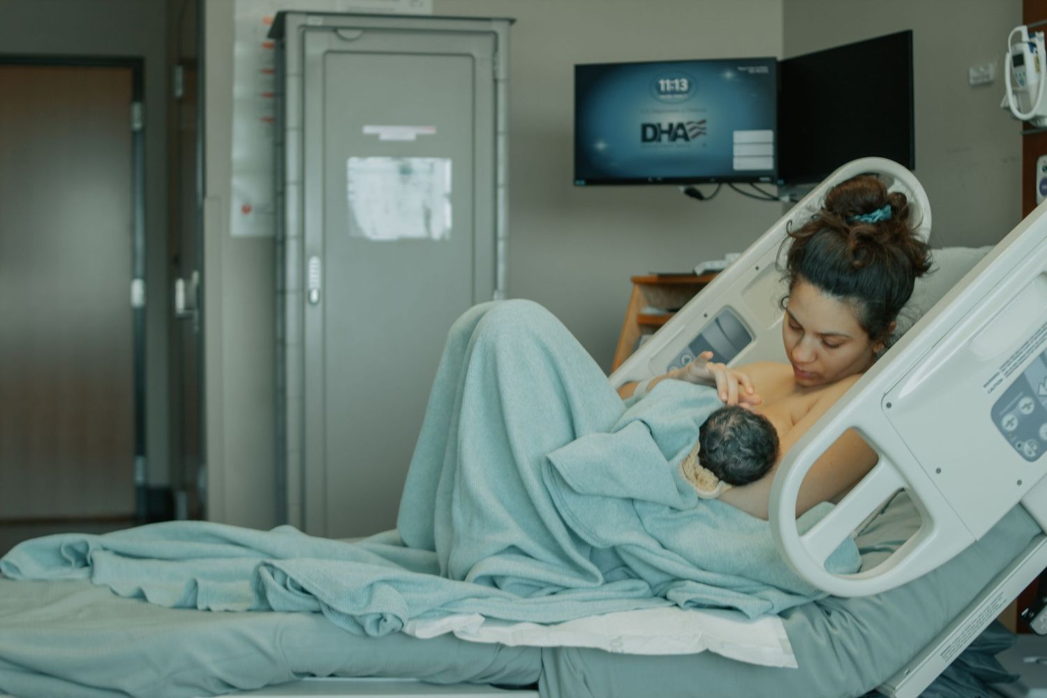 Fort Hood Birth Photographer captures mother nursing baby in hospital bed