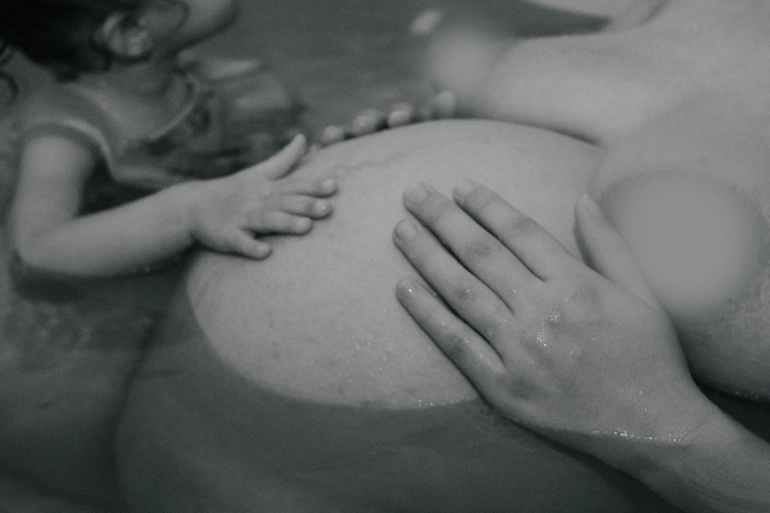 Fort Hood Birth Photographer captures young daughter putting her hand on mom's belly while in labor