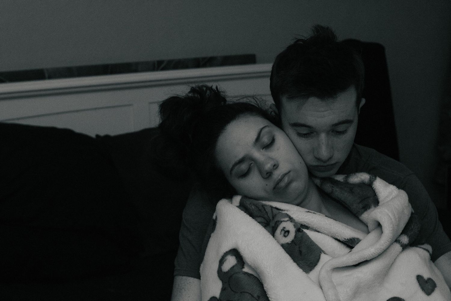 Fort Hood Birth Photographer captures husband hugging laboring wife from behind on the floor of their bedroom