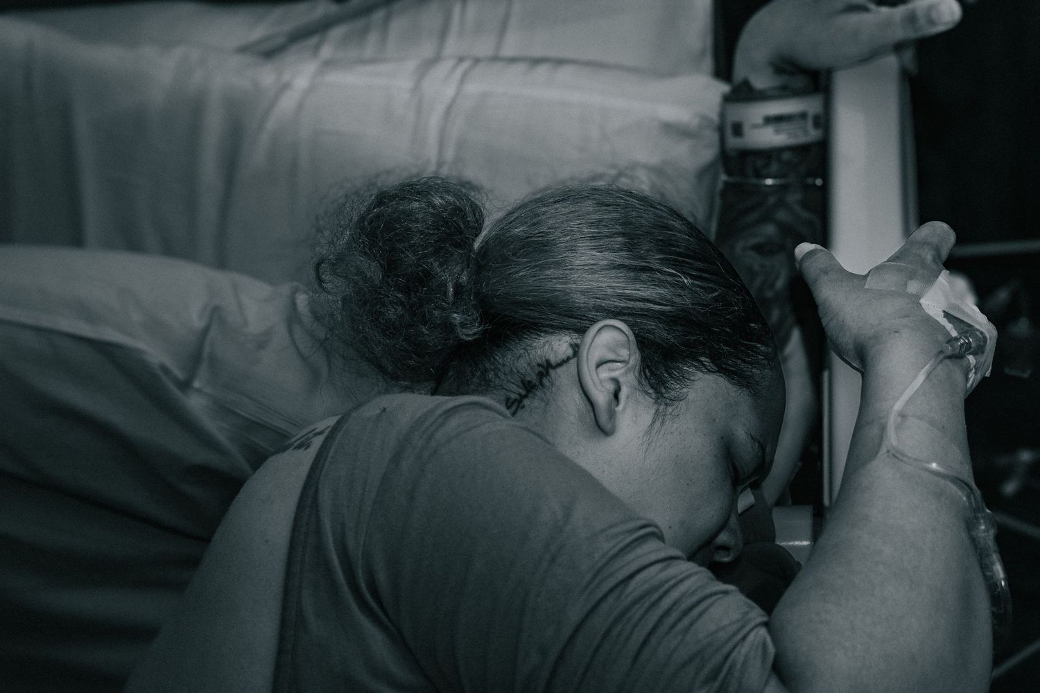 Killeen Birth Photographer captures mother holding on the bed post for strength during hospital labor.