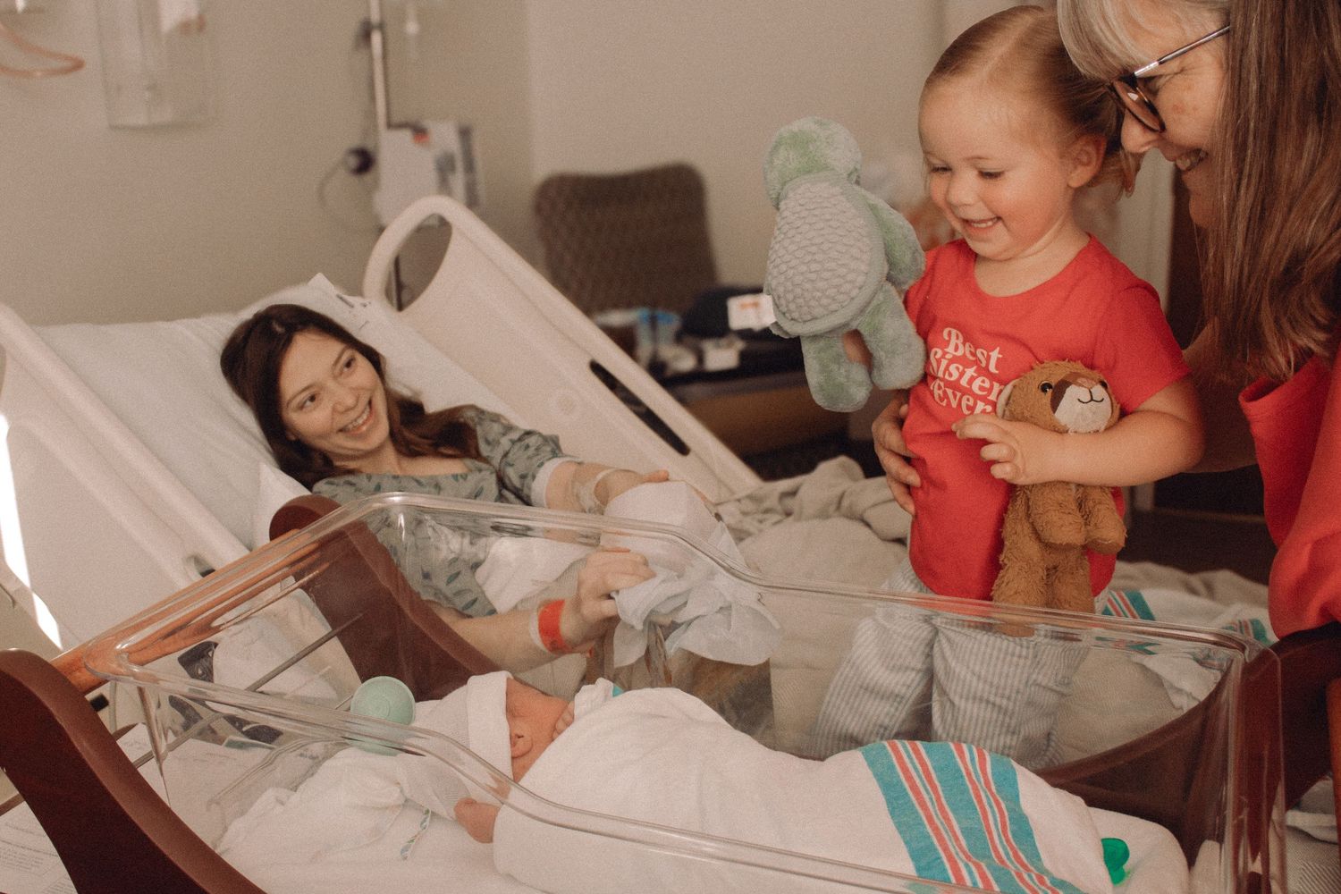 Fresh 48 photographer captures c-section mom introducing her toddler to her baby brother supported by grandma.