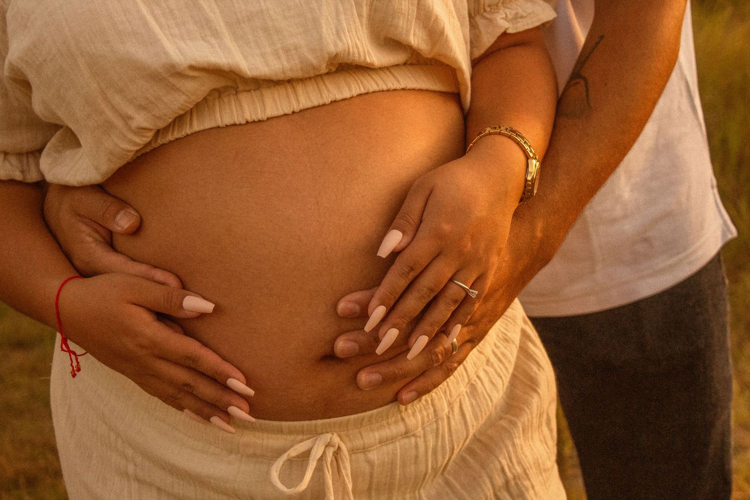 copperas cove maternity photographer capturing husband holding pregnant mother's belly in nature at golden hour.