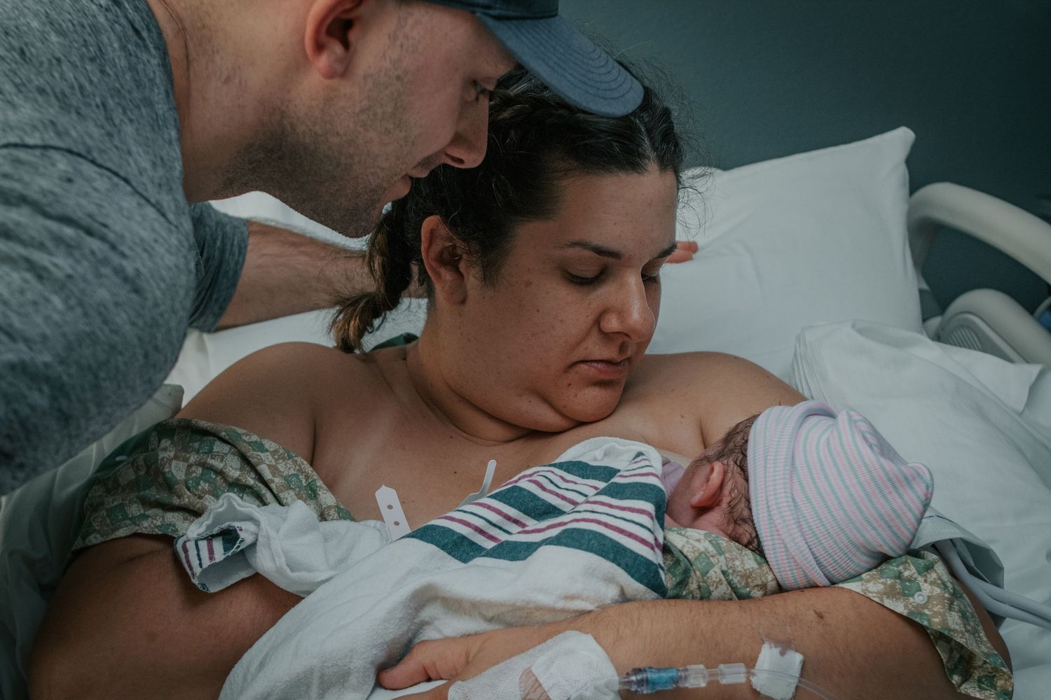 Georgetown Birth Photographer captures mom holding newborn baby and dad looking on lovingly.