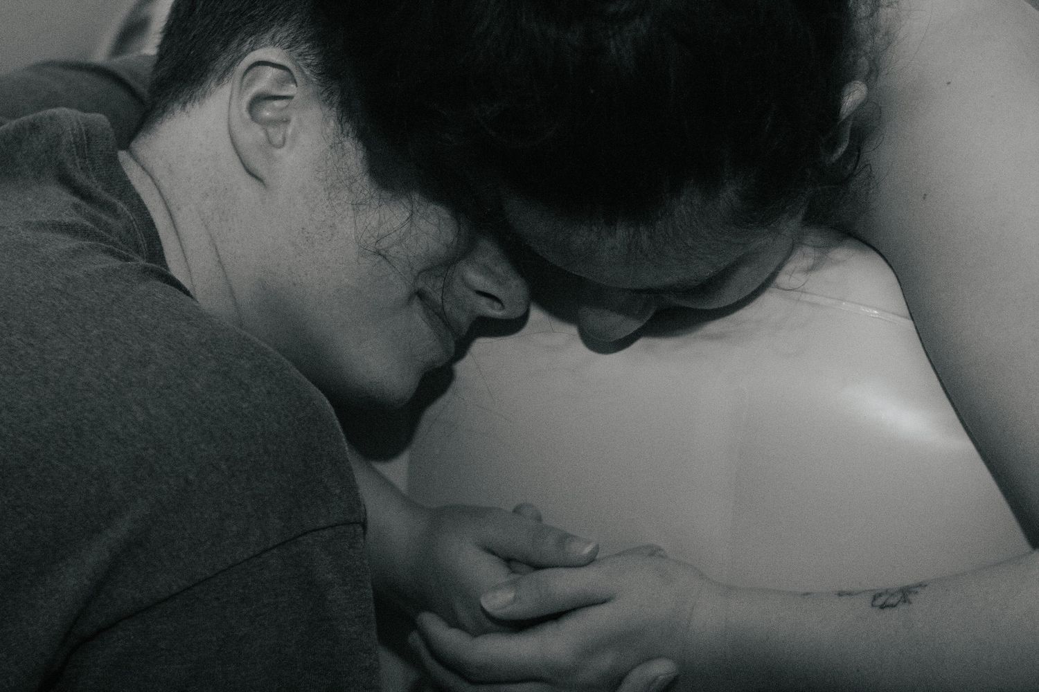Fort Hood Birth Photographer captures husband smiling and hugging his laboring wife.