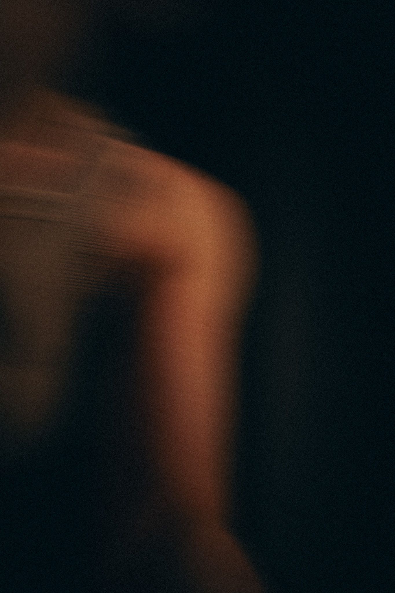 Blurred motion capture in warm tones against deep black background.