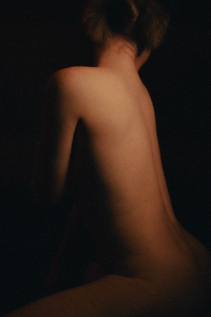 Minimalist body contour photography with soft lighting against black backdrop.