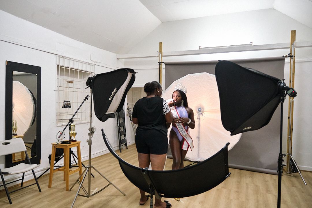 Professional photo studio interior with lighting equipment and backdrop stands in white room.