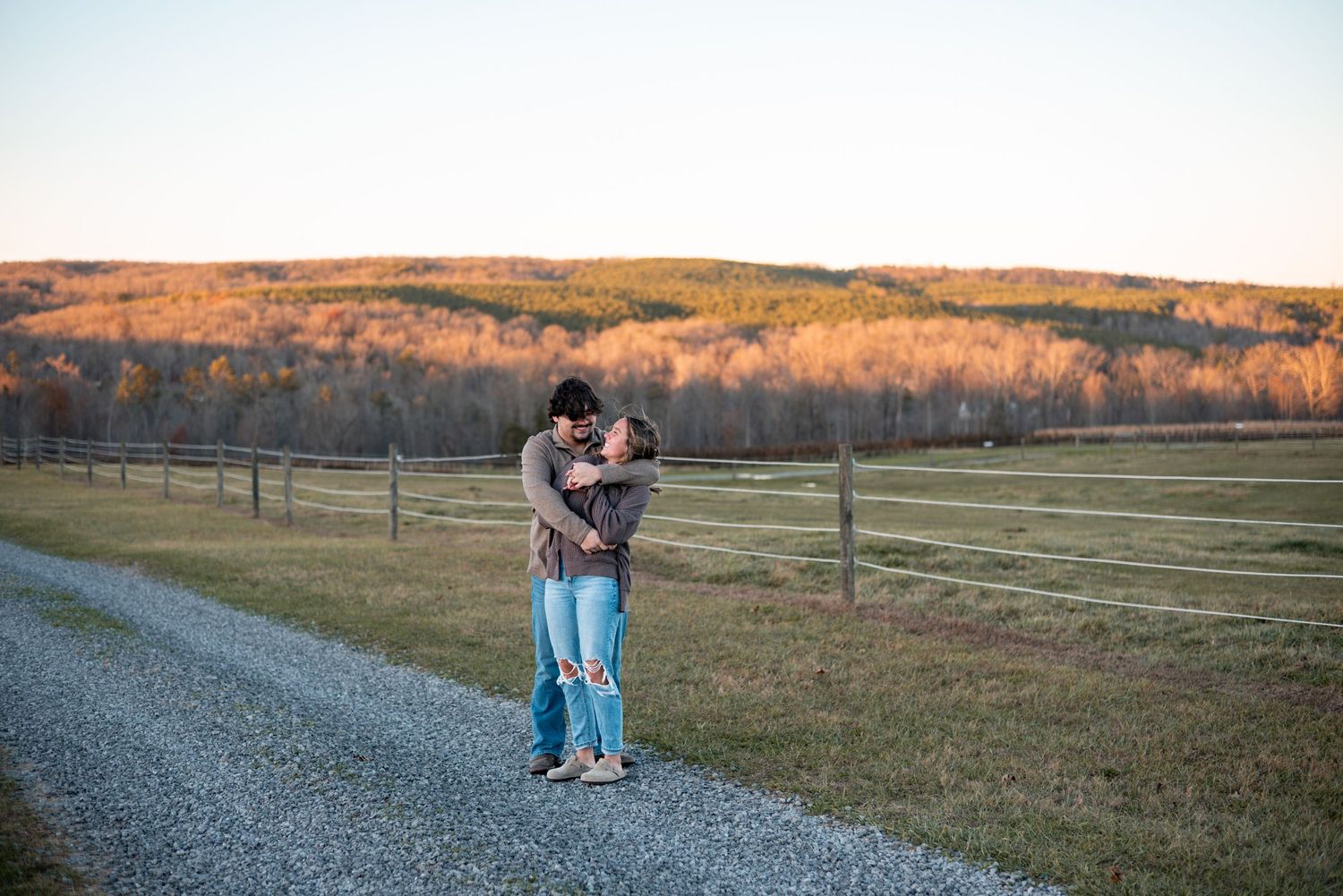 A couple shares tender moments in an open field during sunset.