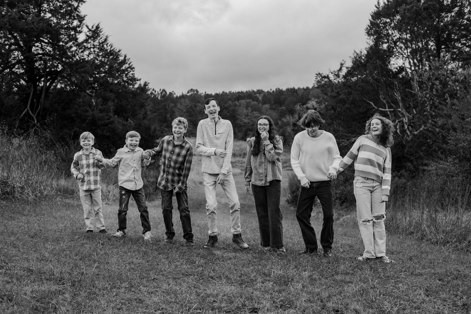 Black and white group portrait of people standing together in a grassy field.