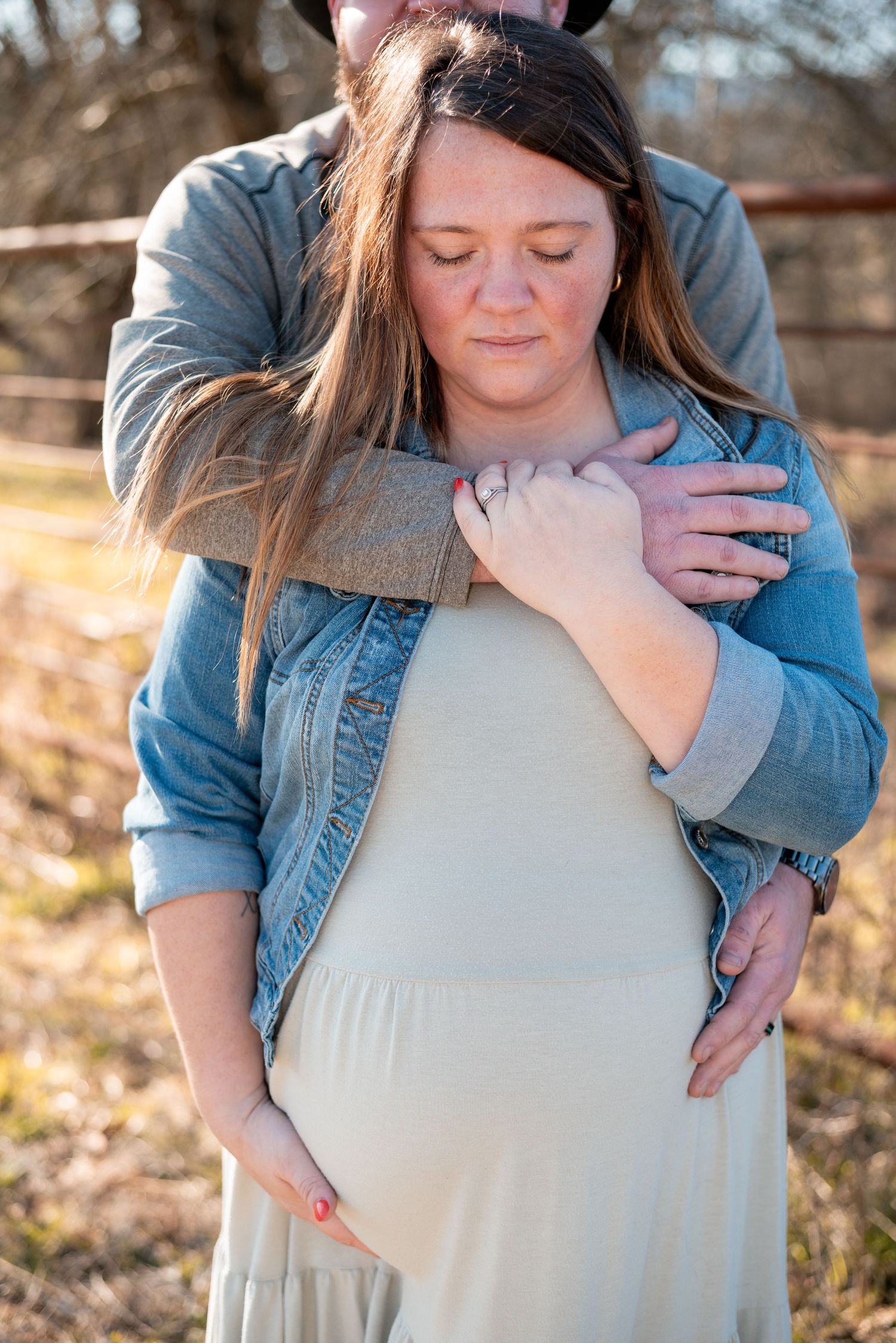 A tender embrace captures an intimate maternity moment in warm sunset light.