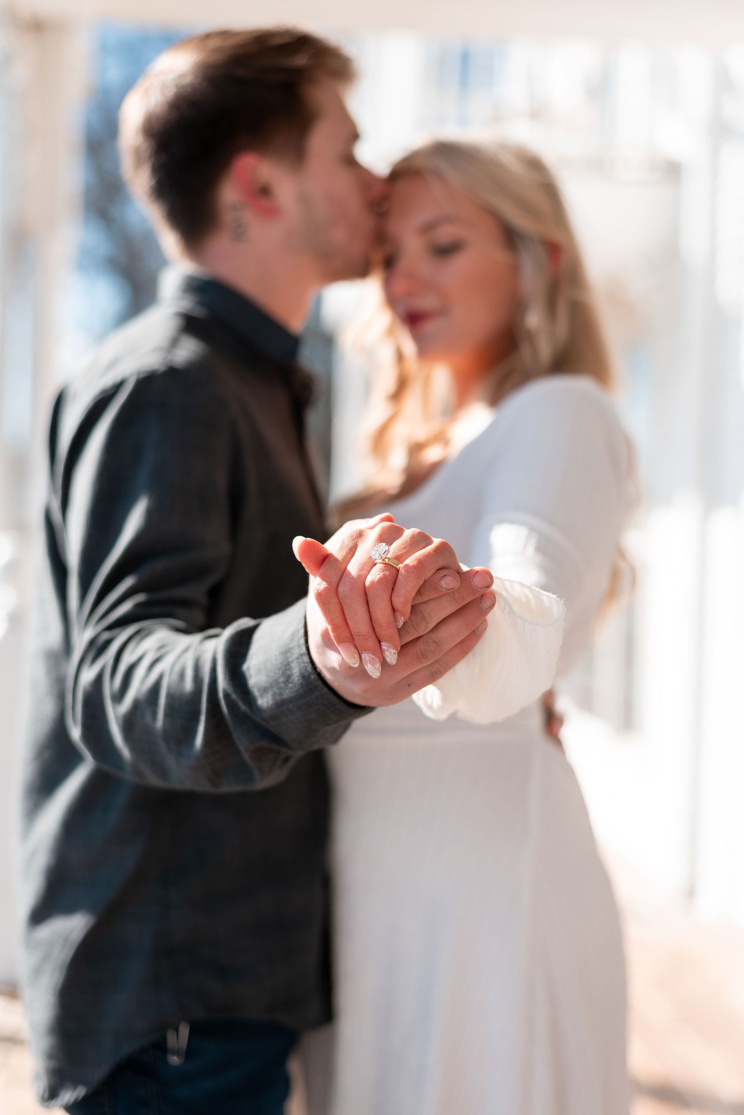 Couple in formal wear dancing together in soft natural light.