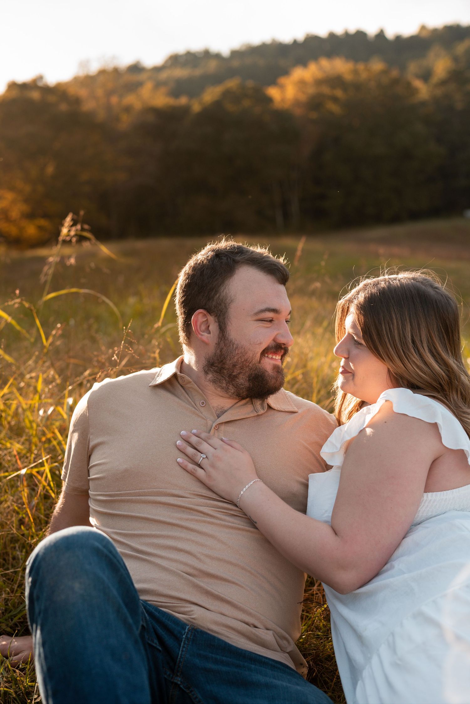 Couple lying in grass sharing intimate moments during sunset photoshoot.