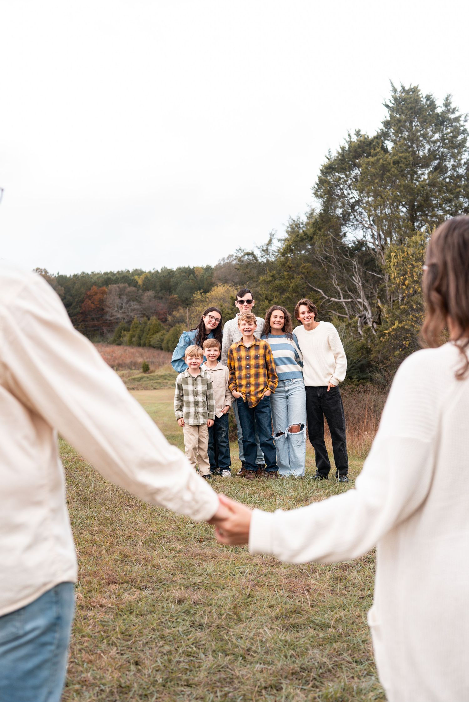 Group forming a human chain with white sweaters in an outdoor fall setting.