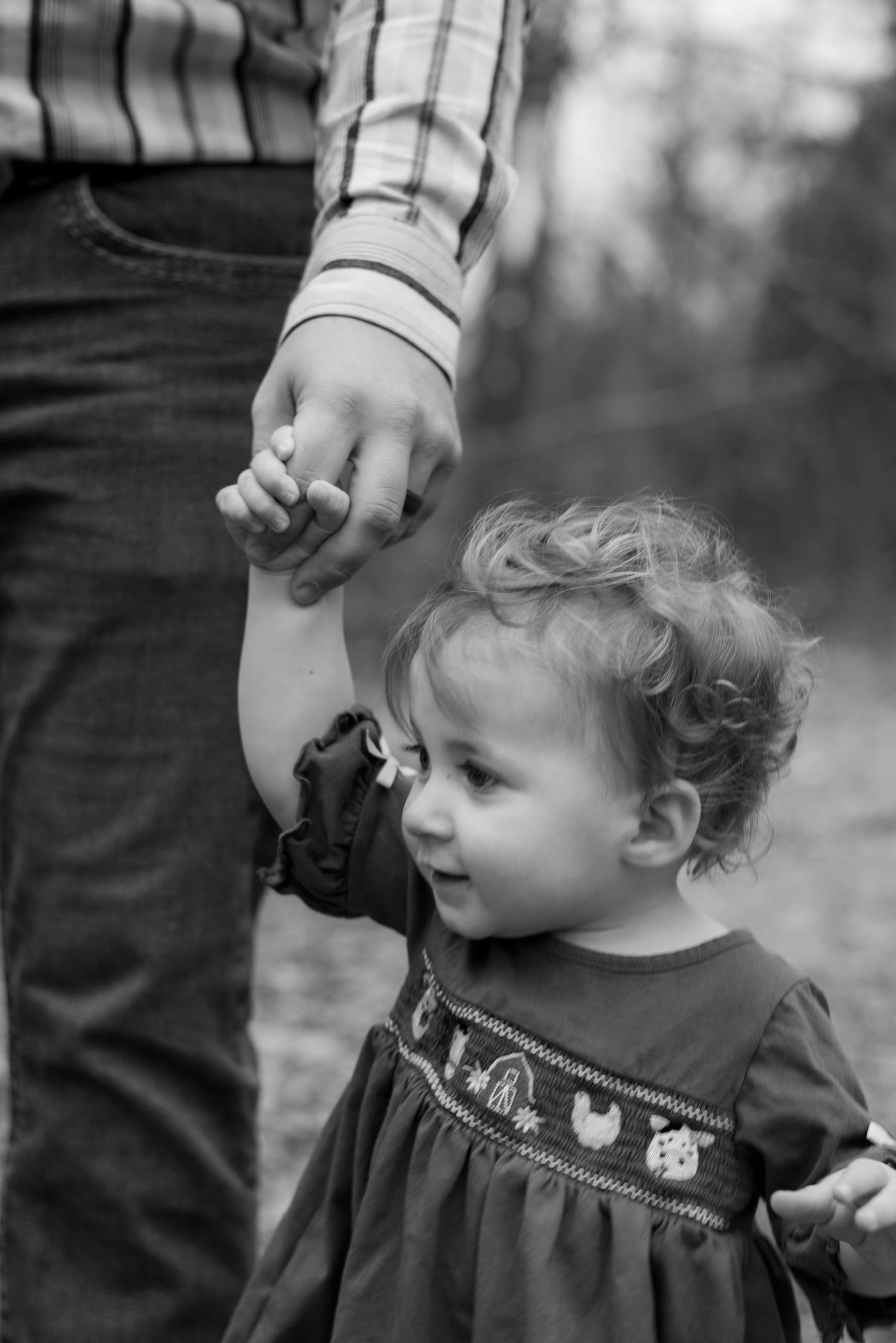 Black and white close-up showing sweet details of a child's dress and gentle interaction.