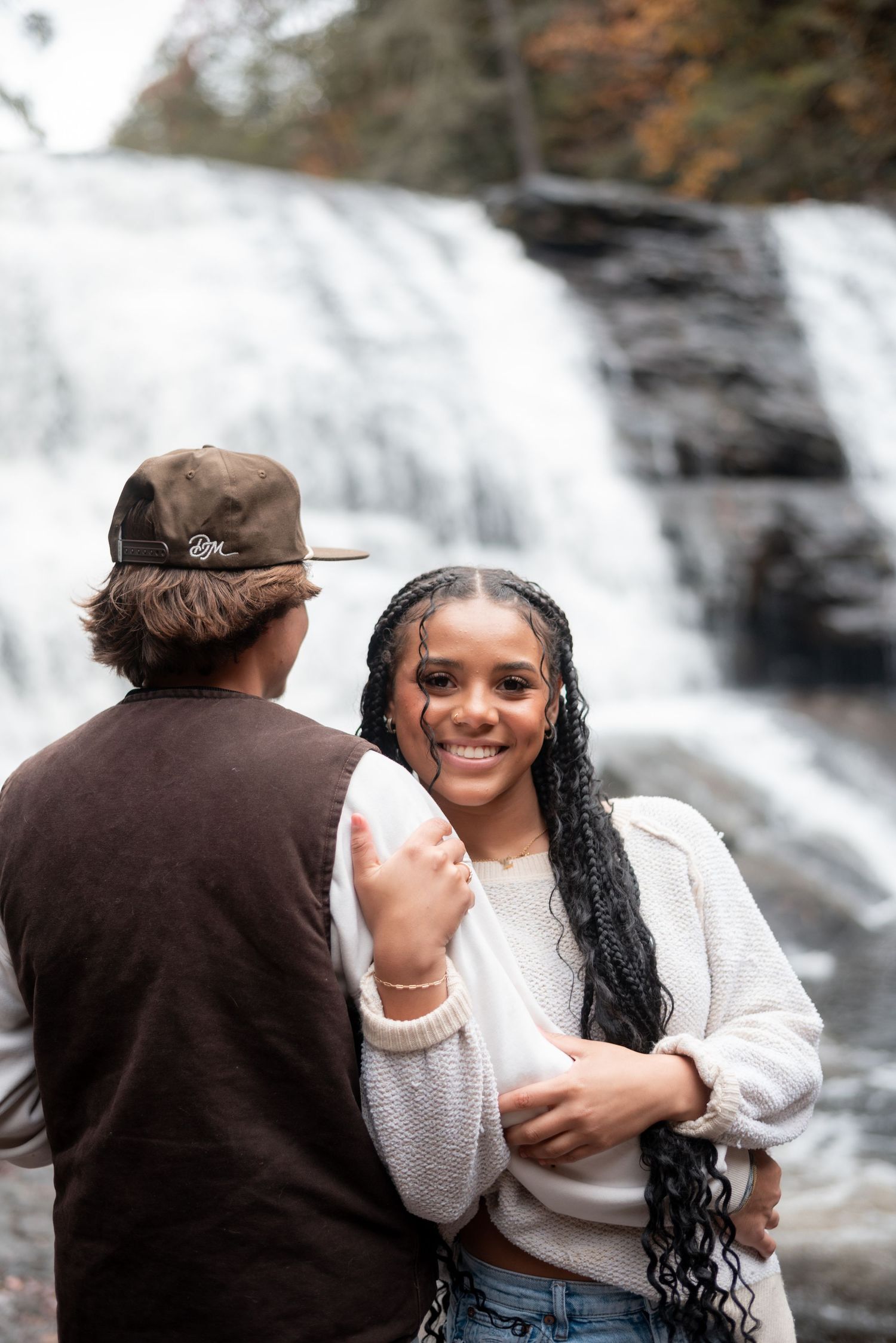 A couple shares joyful moments by a cascading waterfall.