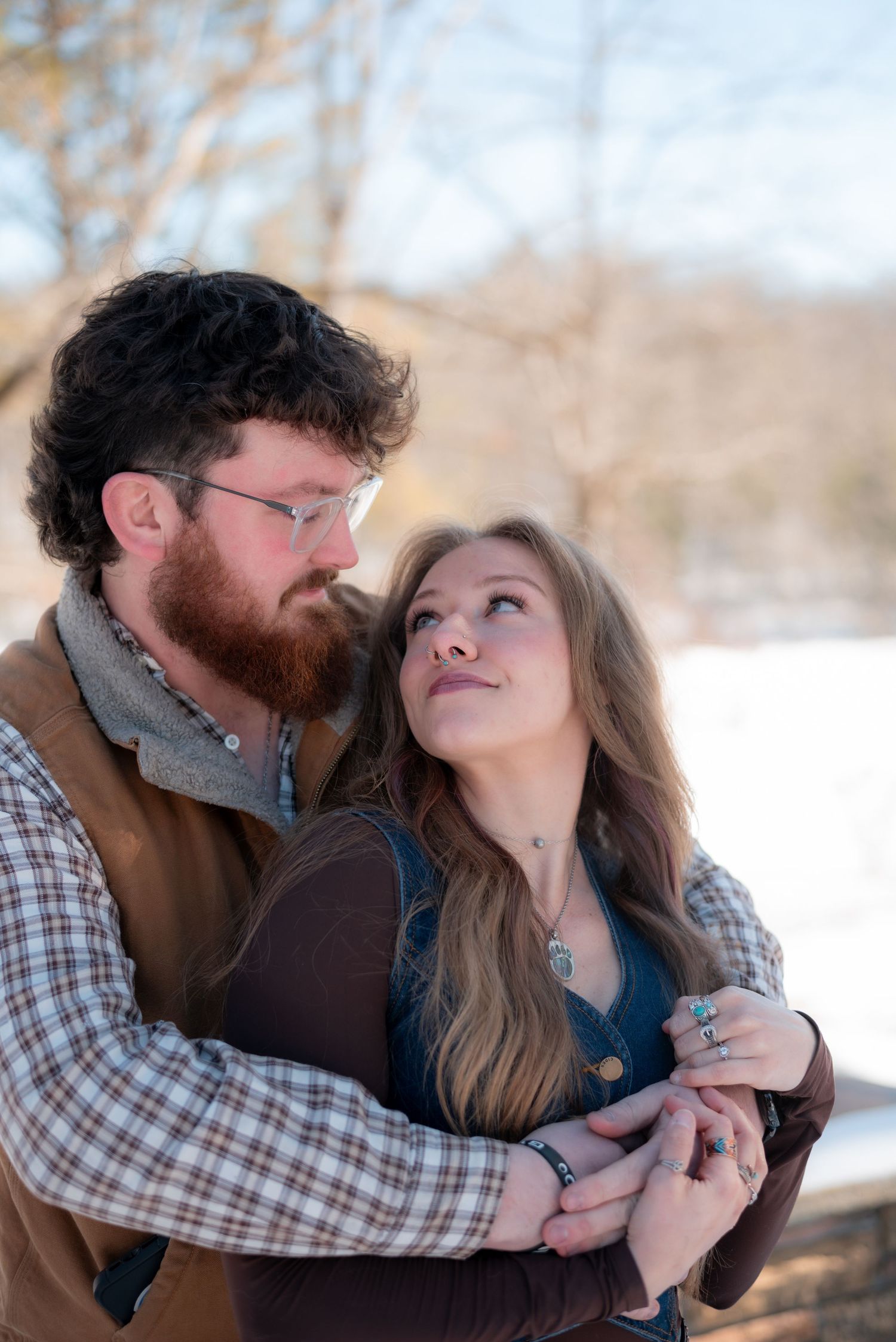 Couple in rustic winter clothing sharing an intimate moment in snowy setting.