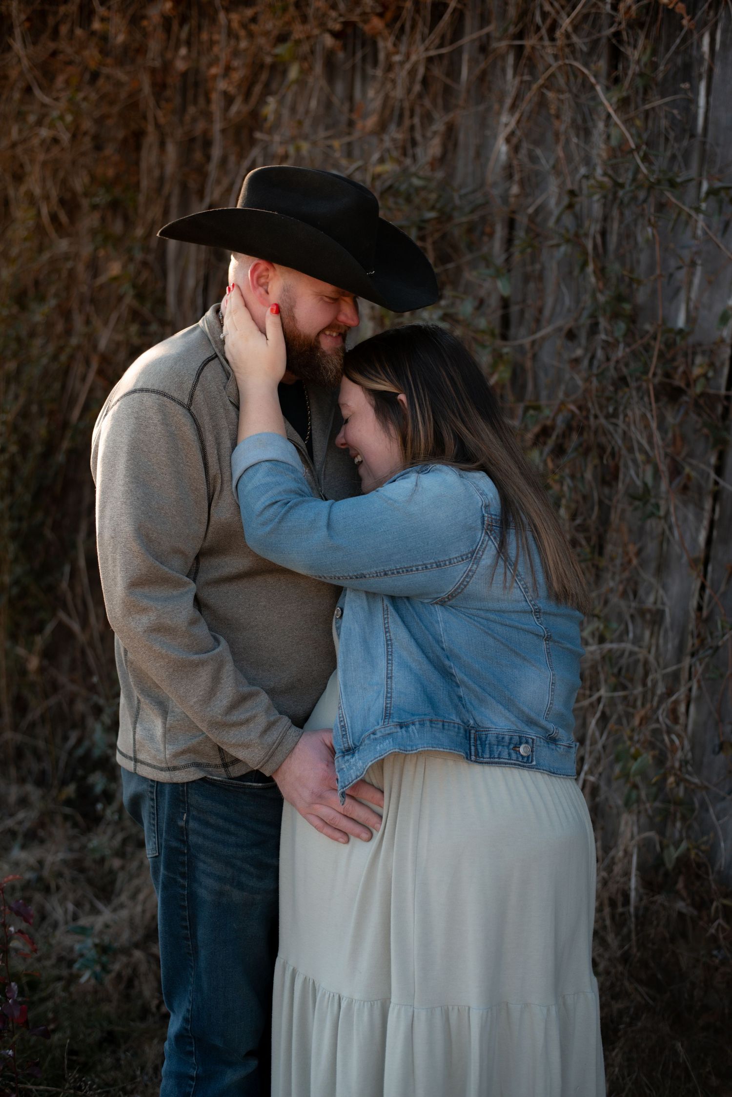 Intimate maternity portraits against rustic backdrop showing couple's tender moments.