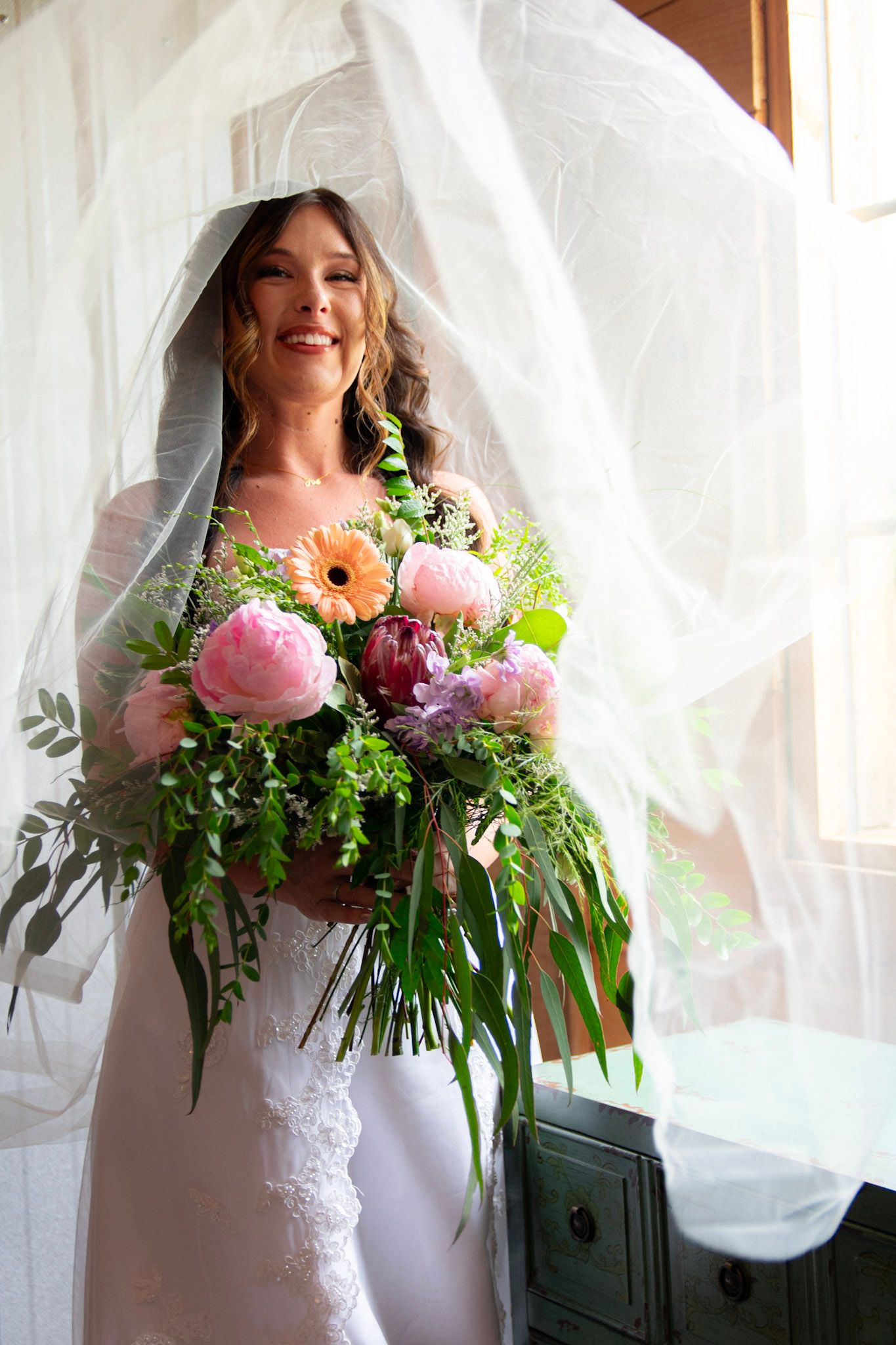 Bridal portraits with flowing white veil and vibrant pink floral bouquet.
