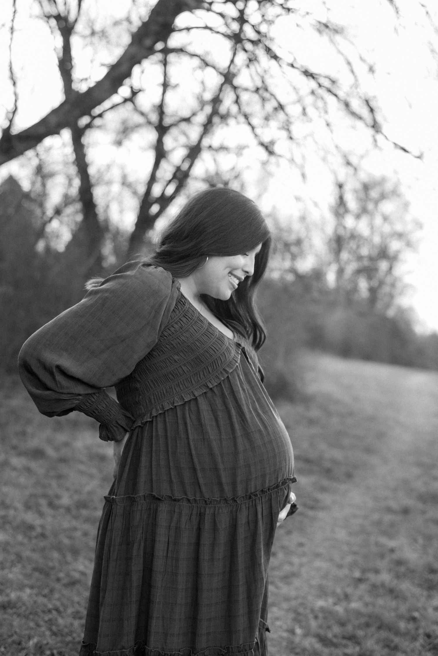 Side view of a brown dress against a natural outdoor background with bare trees.