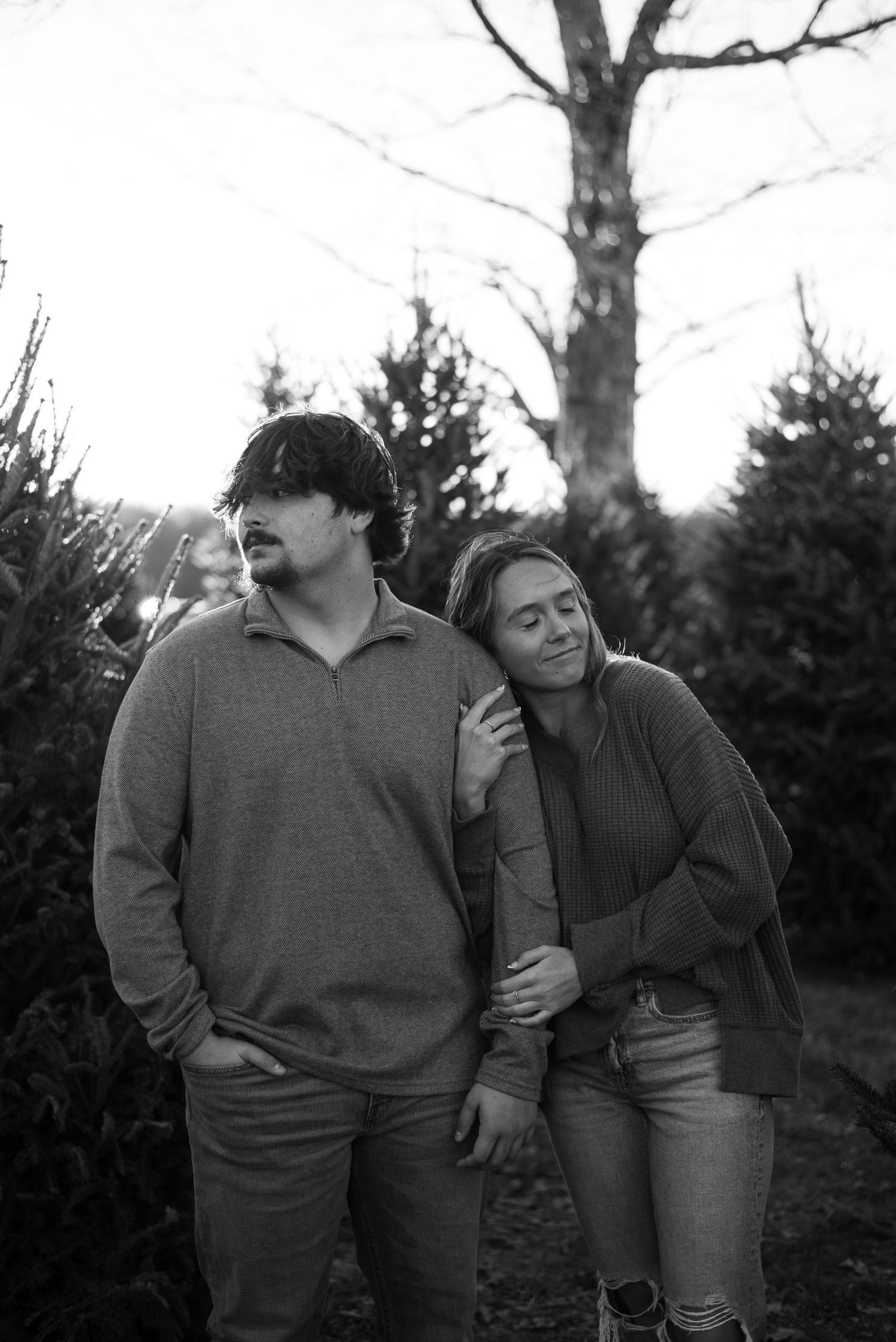 Couple in casual winter wear sharing affectionate moments in a forest setting.