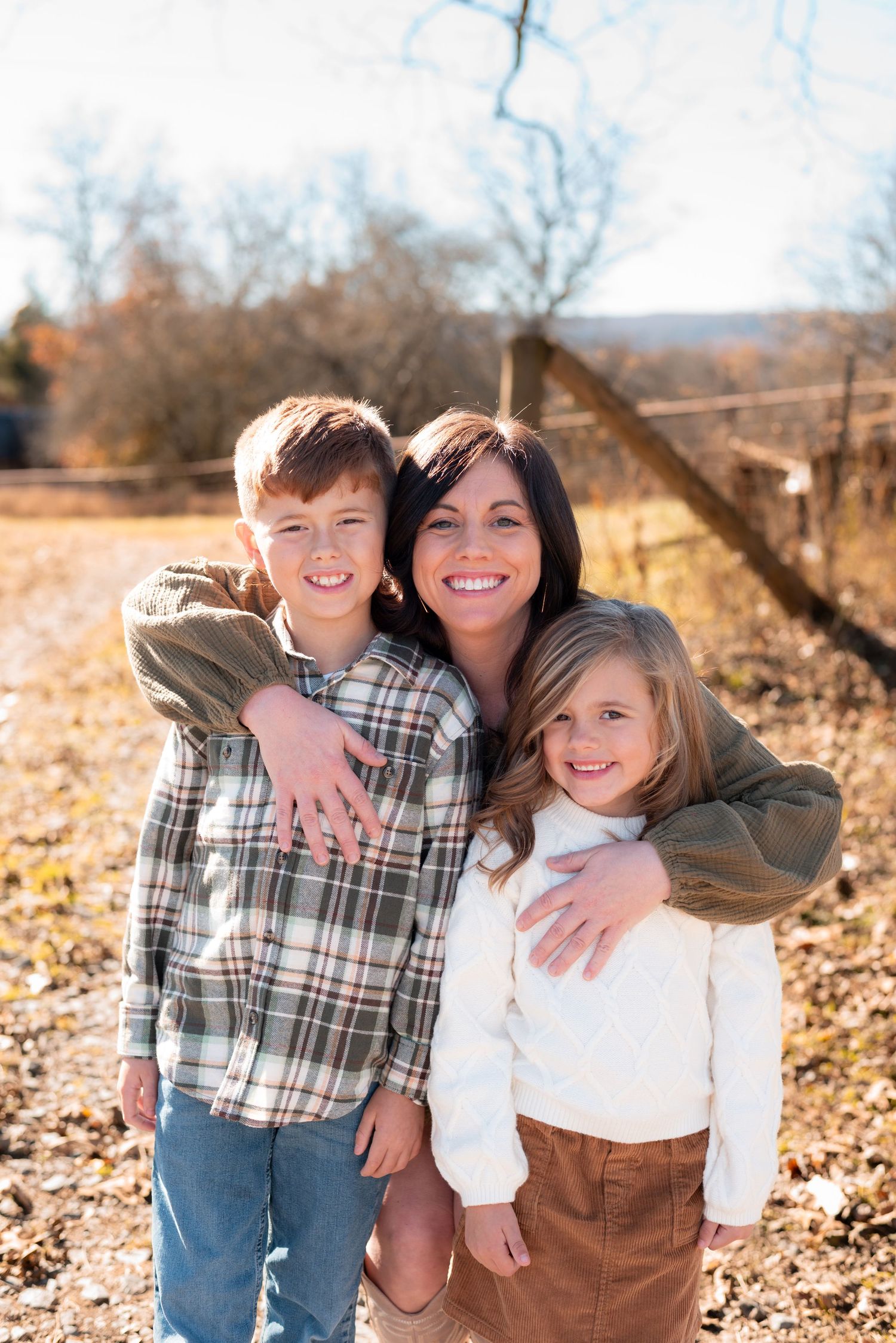 Outdoor family portrait with plaid and white shirts against autumn background.