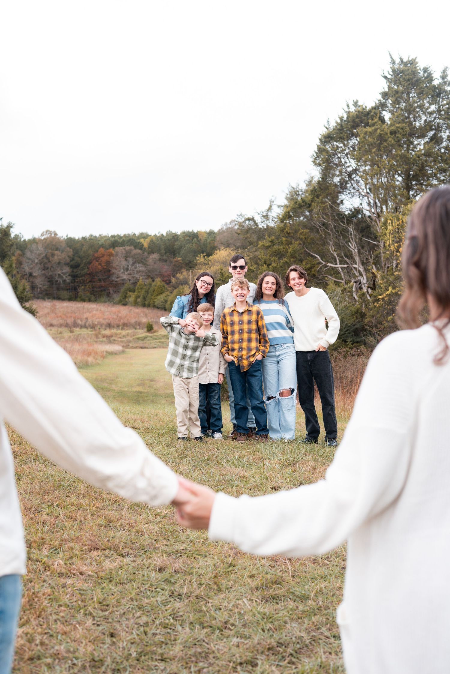 People linked together in white tops creating a line across a grassy field.