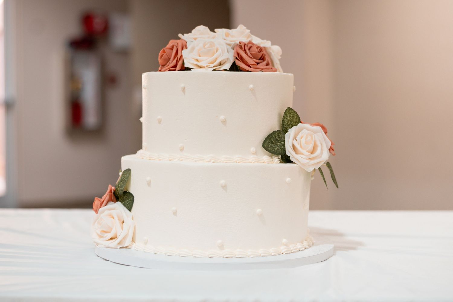 Elegant white wedding cake decorated with delicate pink roses.