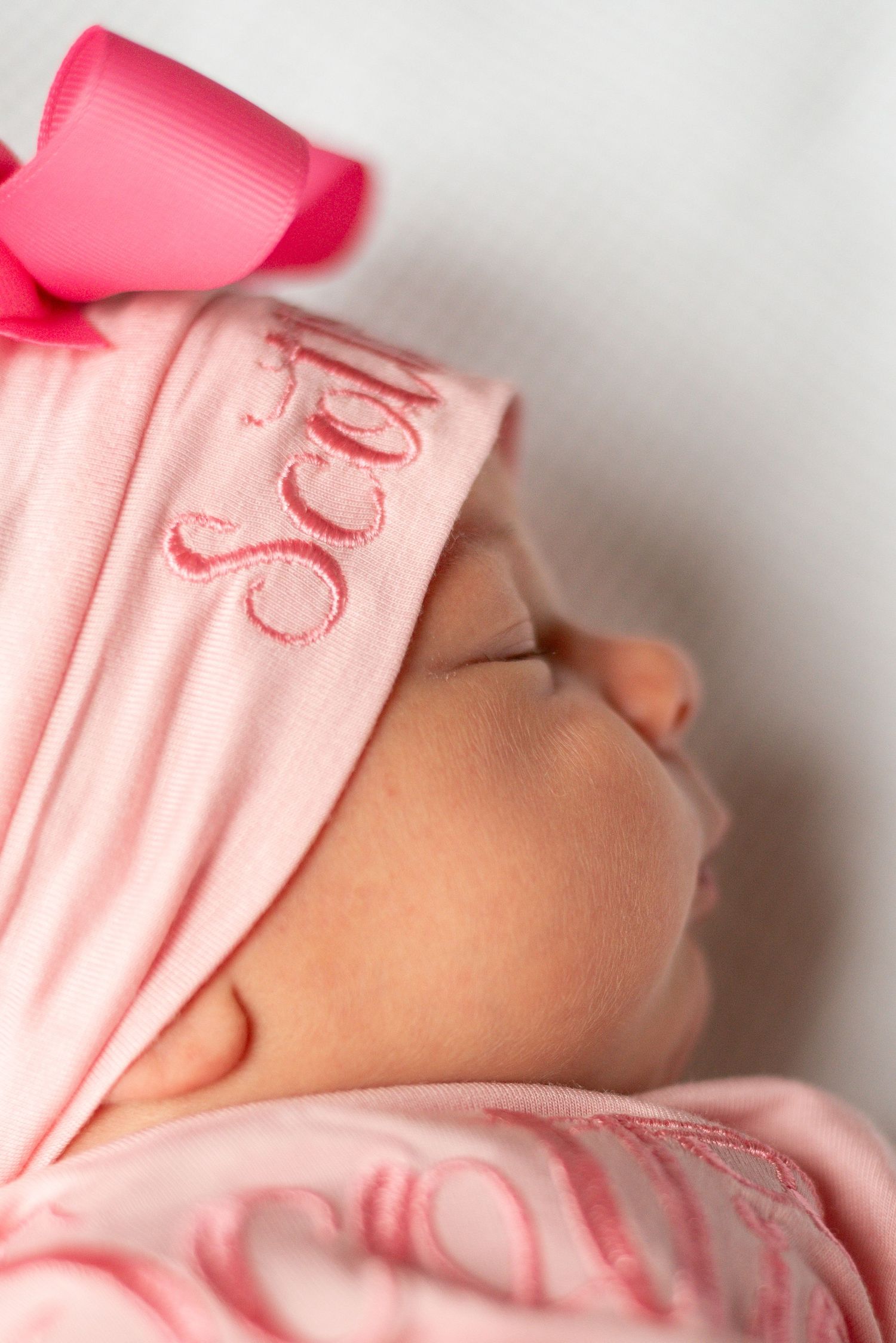 Close-up of soft pink baby clothing details against white backdrop.