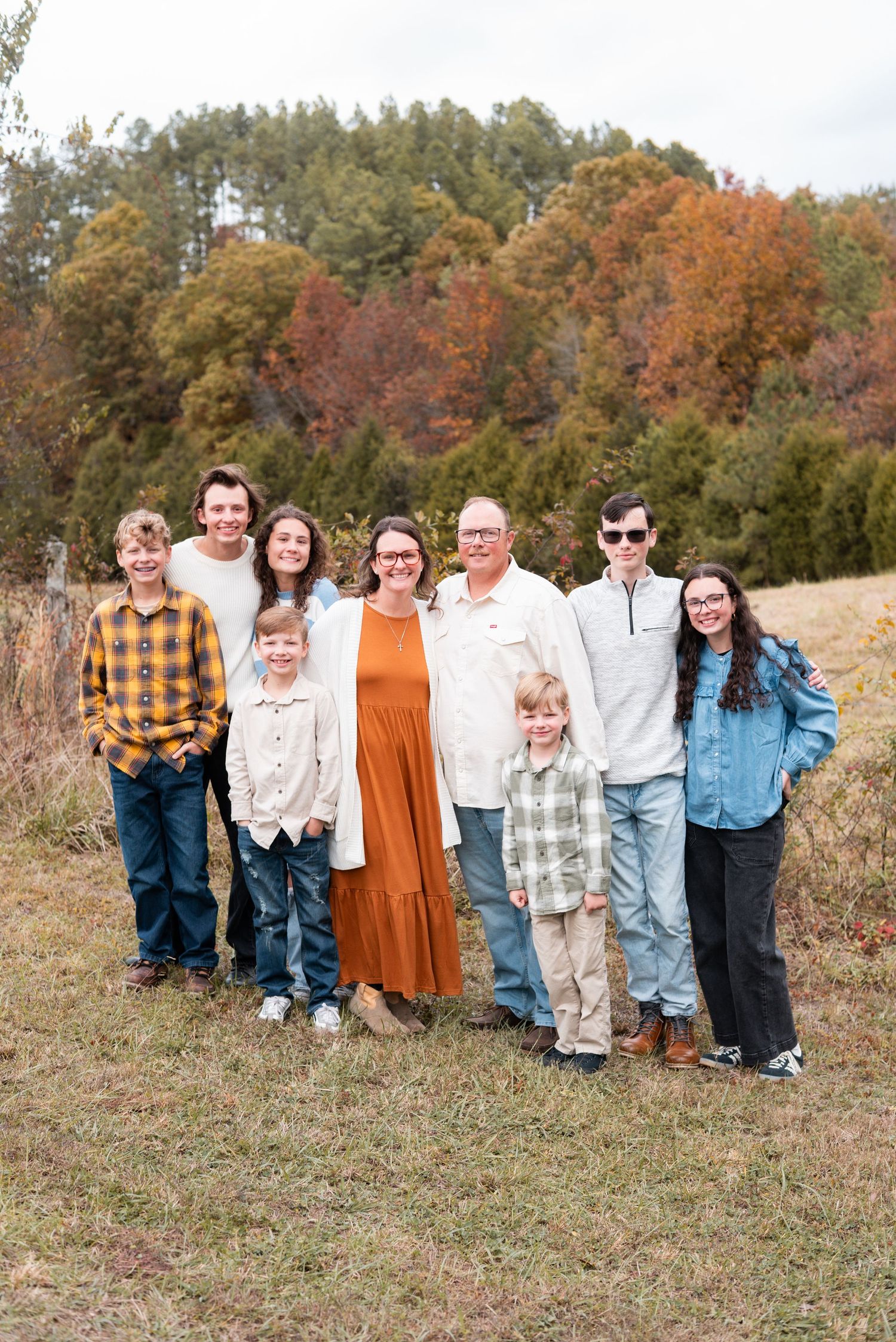 Large family group poses together on hillside during fall photo session.