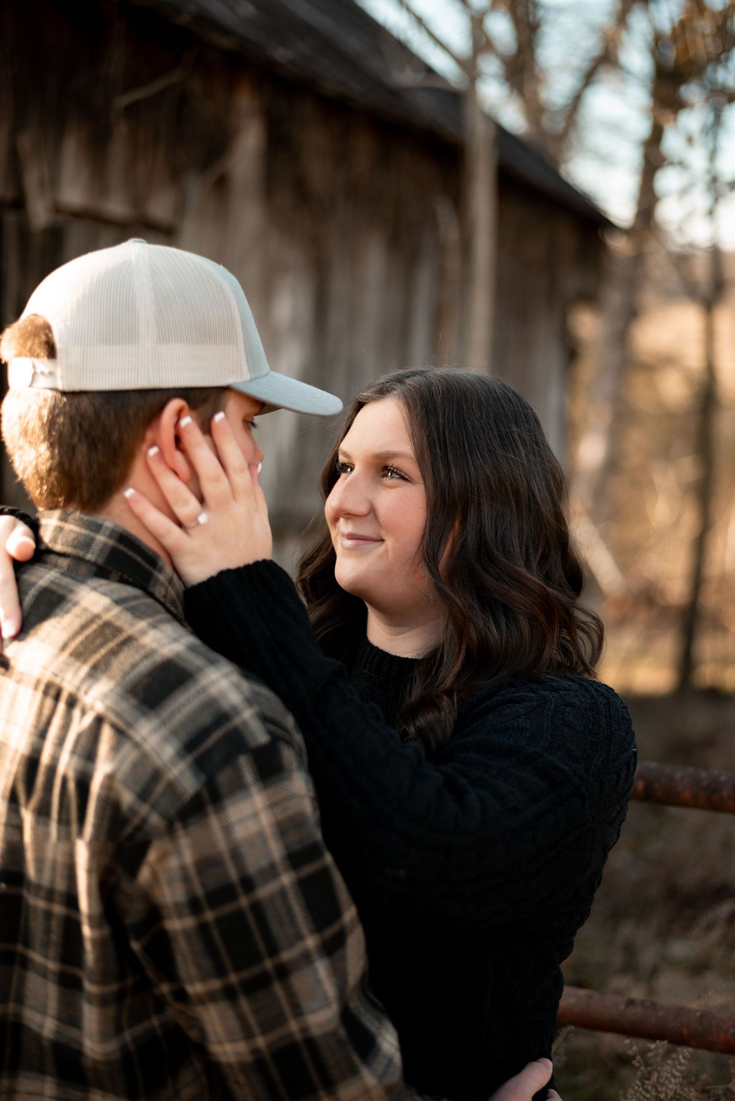 Romantic couple sharing an intimate moment against a rustic barn backdrop at sunset.
